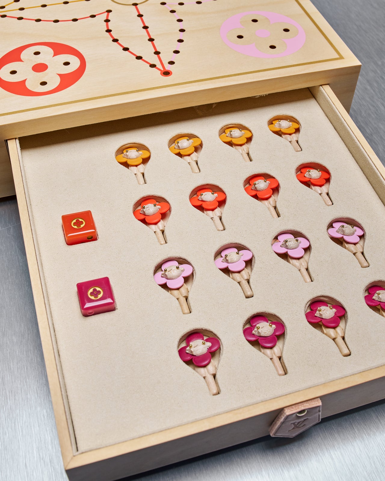 Louis Vuitton game board with colorful markers and a die on a wooden surface