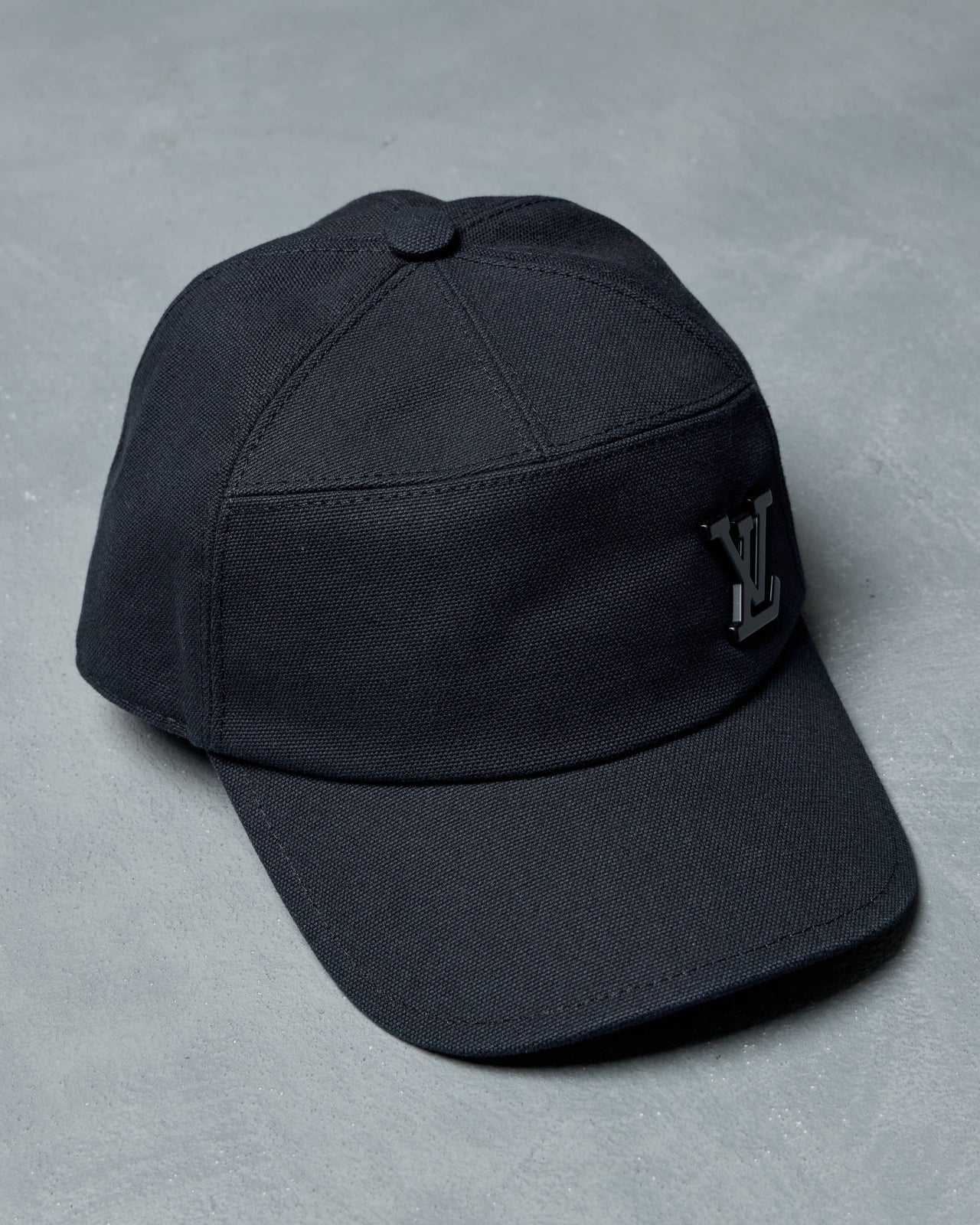 Black Louis Vuitton cap with a logo on a gray background