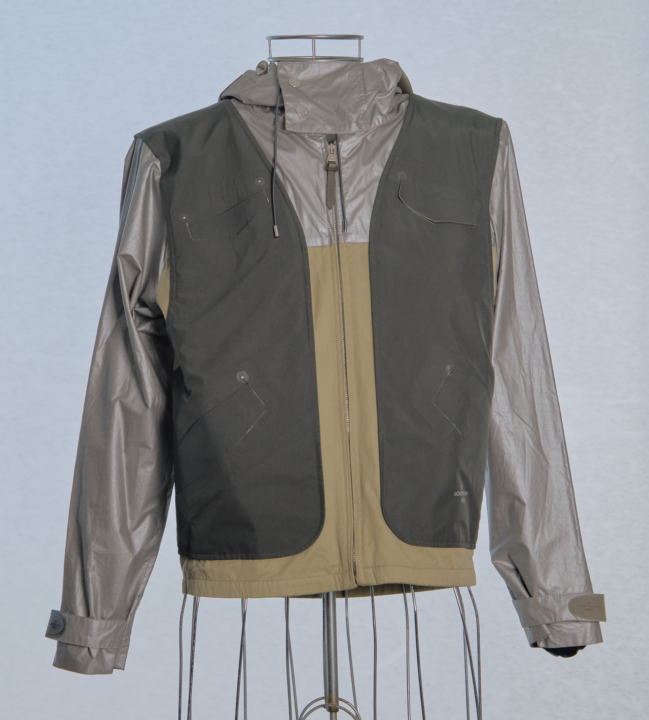 Two-tone Louis Vuitton jacket with dark gray and beige sections on a mannequin against a light blue background