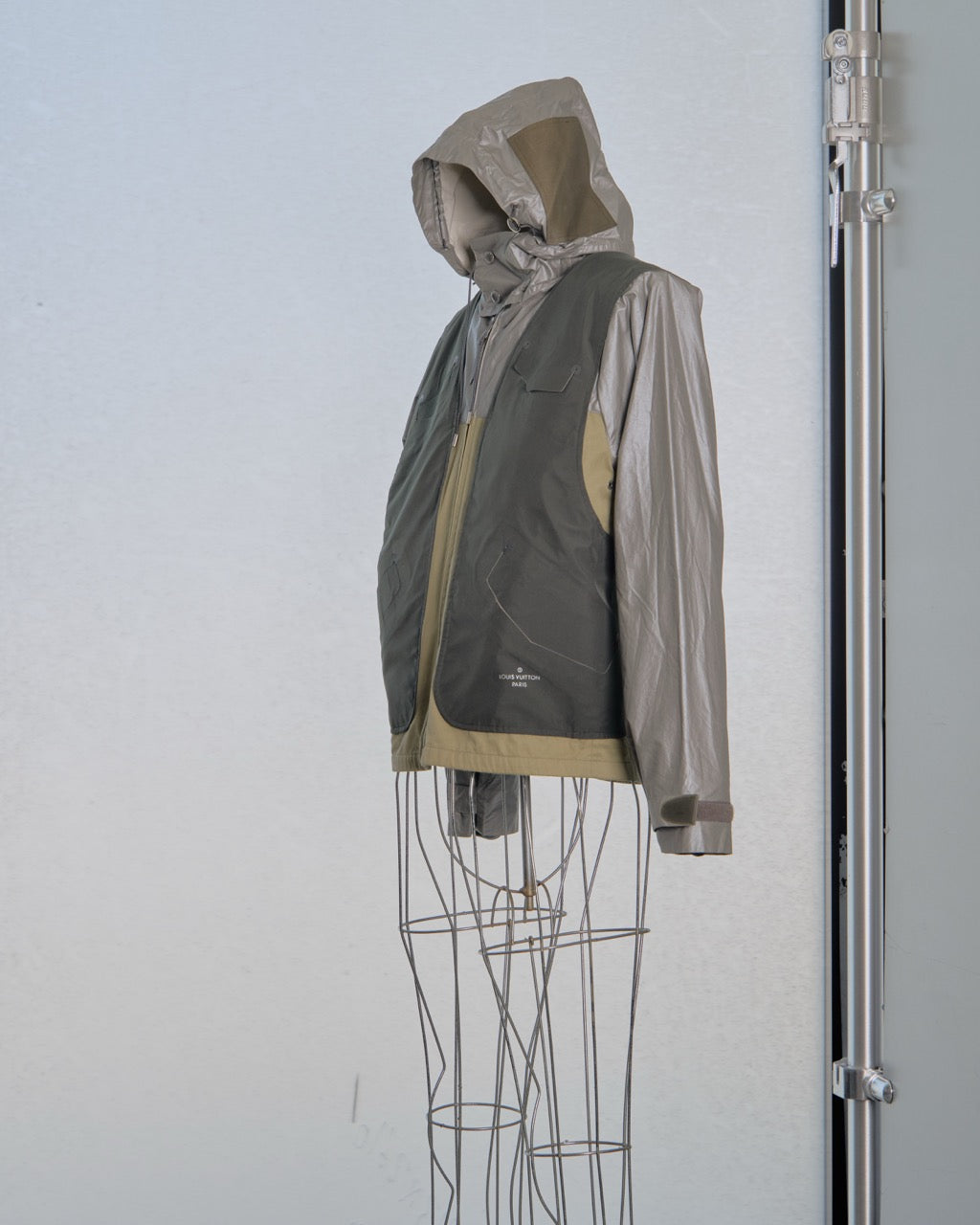 Two-tone Louis Vuitton jacket with dark gray and beige sections on a mannequin against a light blue background