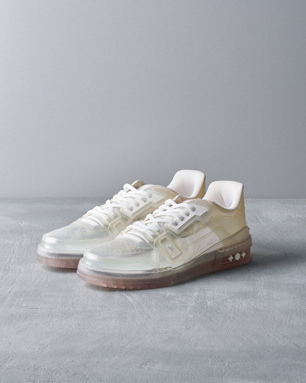 A pair of white Louis Vuitton low sneakers with translucent moulded body and embossed signature on the side.