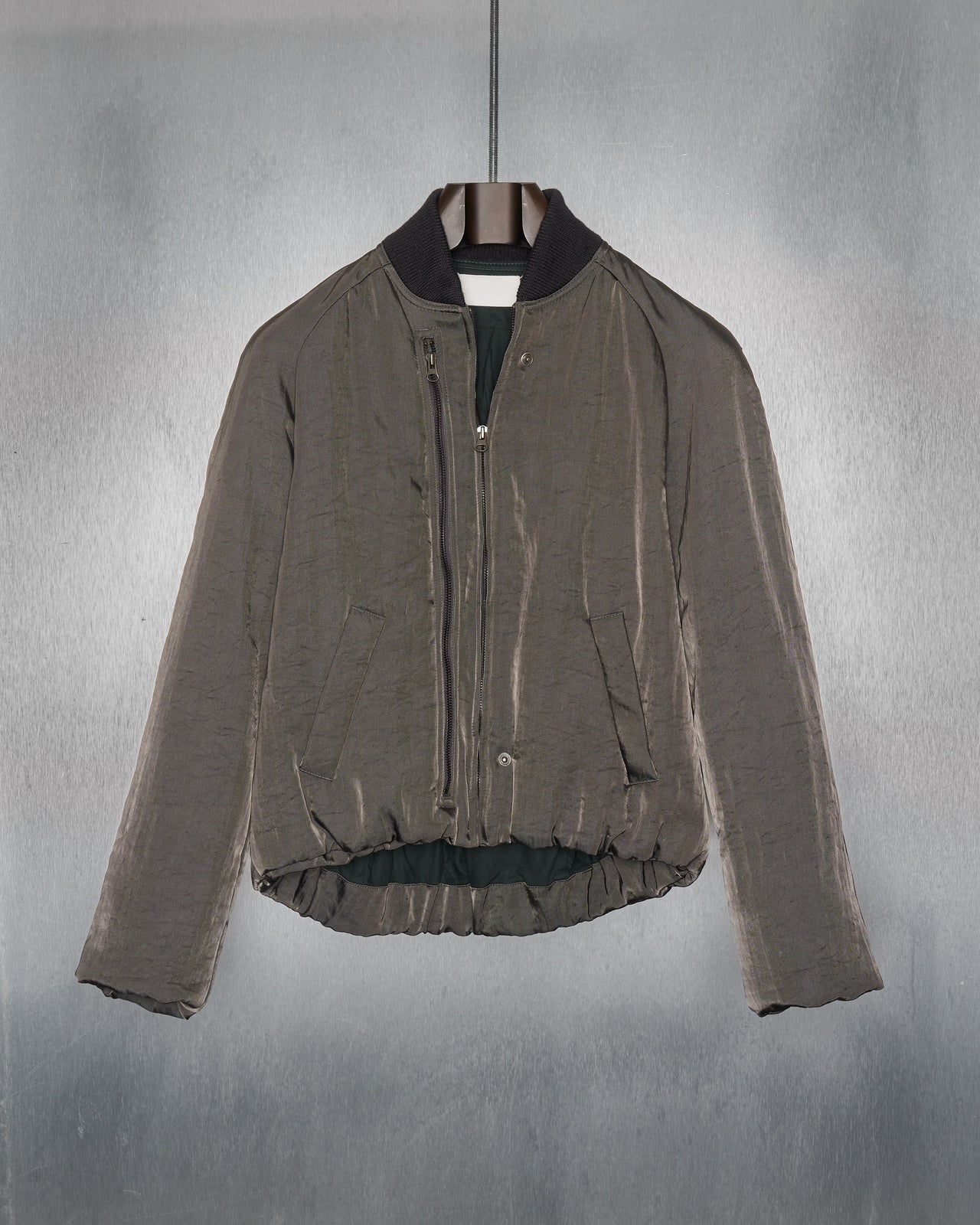 Glistening Maison Margiela bomber jacket in gunmetal twill with pleated panelling on the back and a two-way opening. It features a front picket, zip pockets at hips, and raglan sleeves with hidden rib knit cuffs.