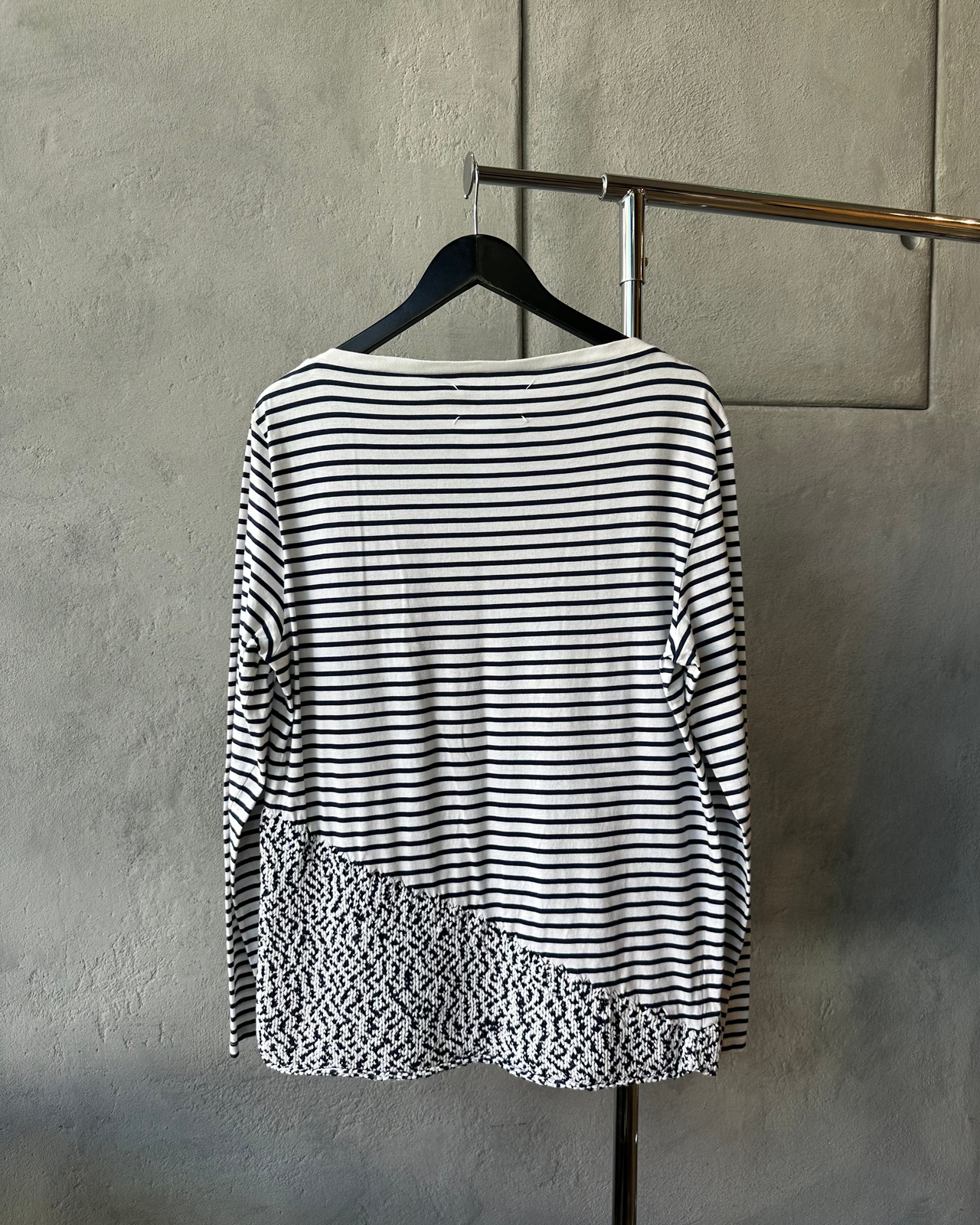 Blue and white striped Maison Margiela shirt with a floral pattern on a hanger against a gray wall.