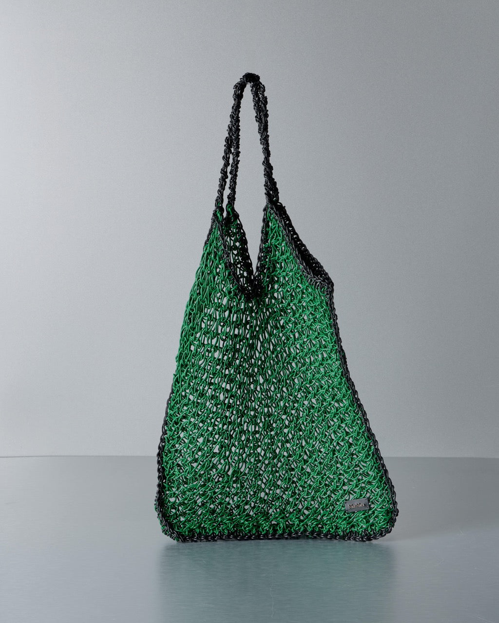 Green textured Max Mara handbag with black handles on a gray background