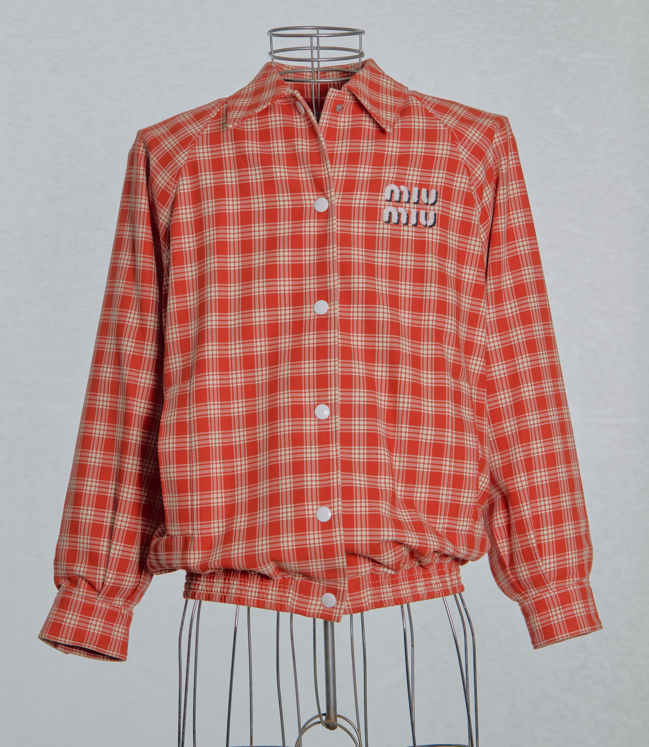 Red plaid Miu Miu jacket with brand logo on a gray background