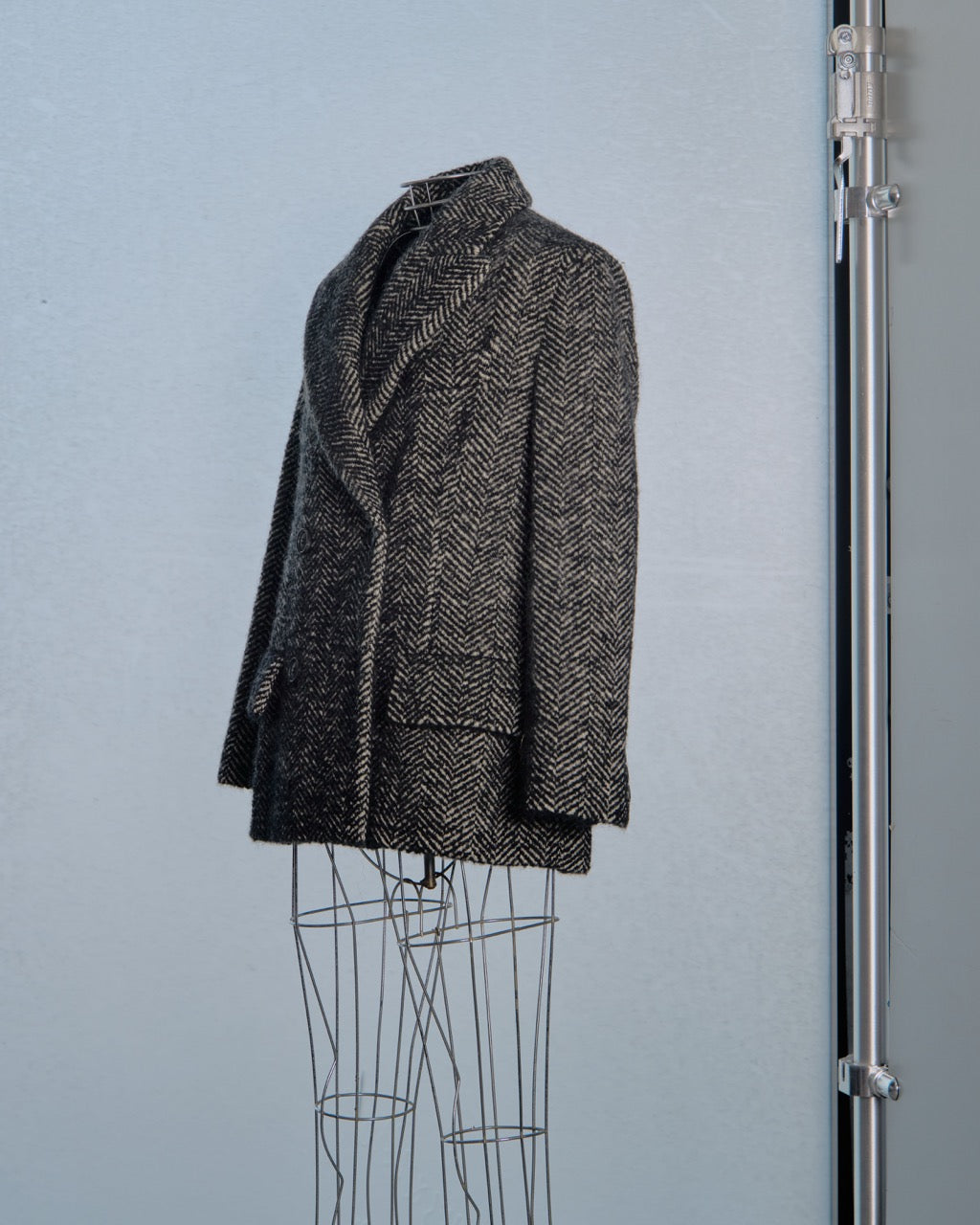 Herringbone Miu Miu patterned coat on a mannequin against a light blue background