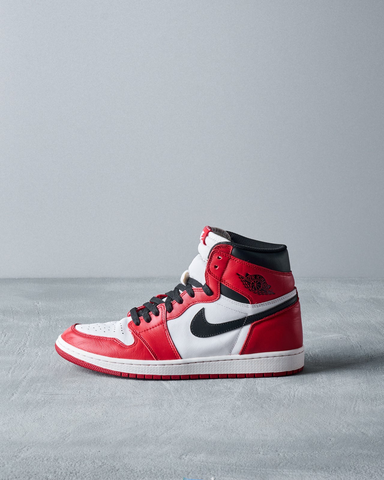 A high-top Nike Air Jordan 1 Retro High OG 'Chicago' sneaker in red, white, and black colors with a lace-up closure and Nike Air logo on the tongue.