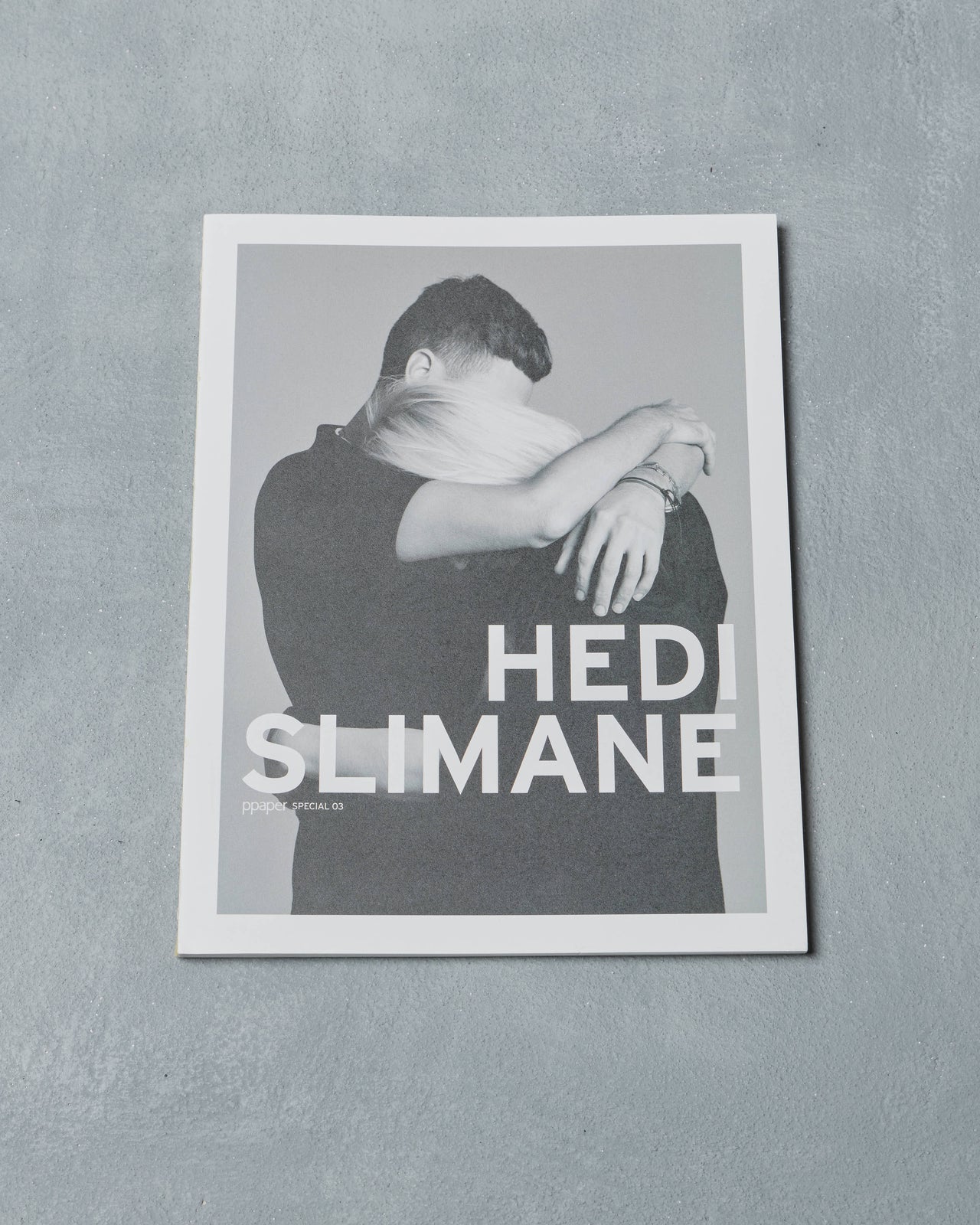 Ppaper Magazine cover with a person embracing and 'Hedi Slimane' text on a gray background