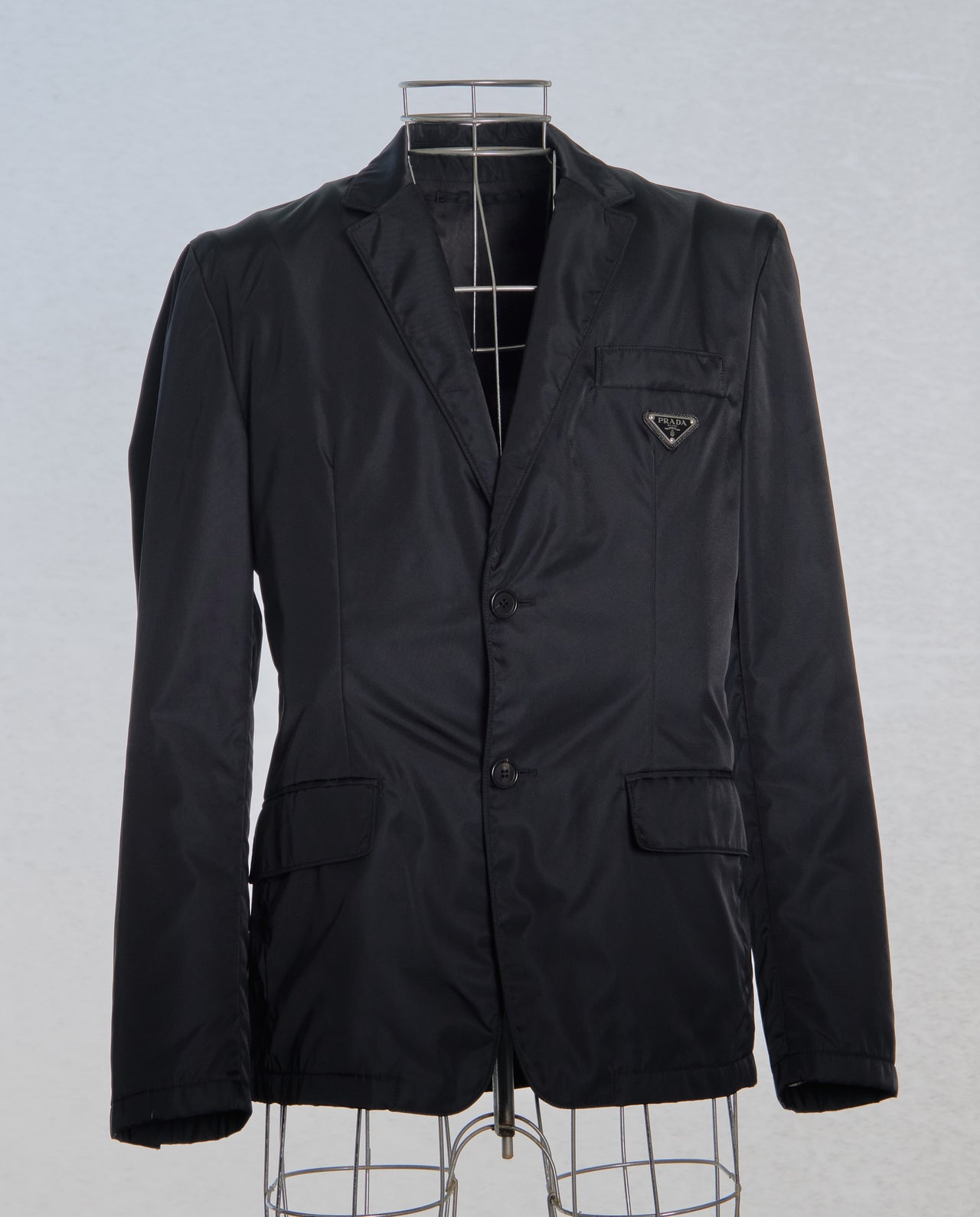 Black nylon Prada jacket on a mannequin against a light gray background