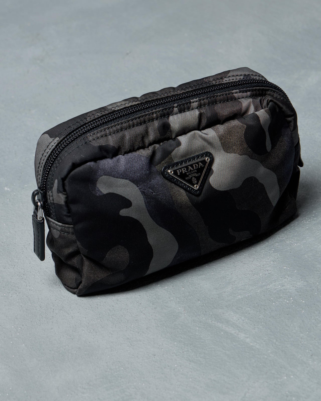 Prada Camouflage-patterned pouch with a brand logo on a gray background