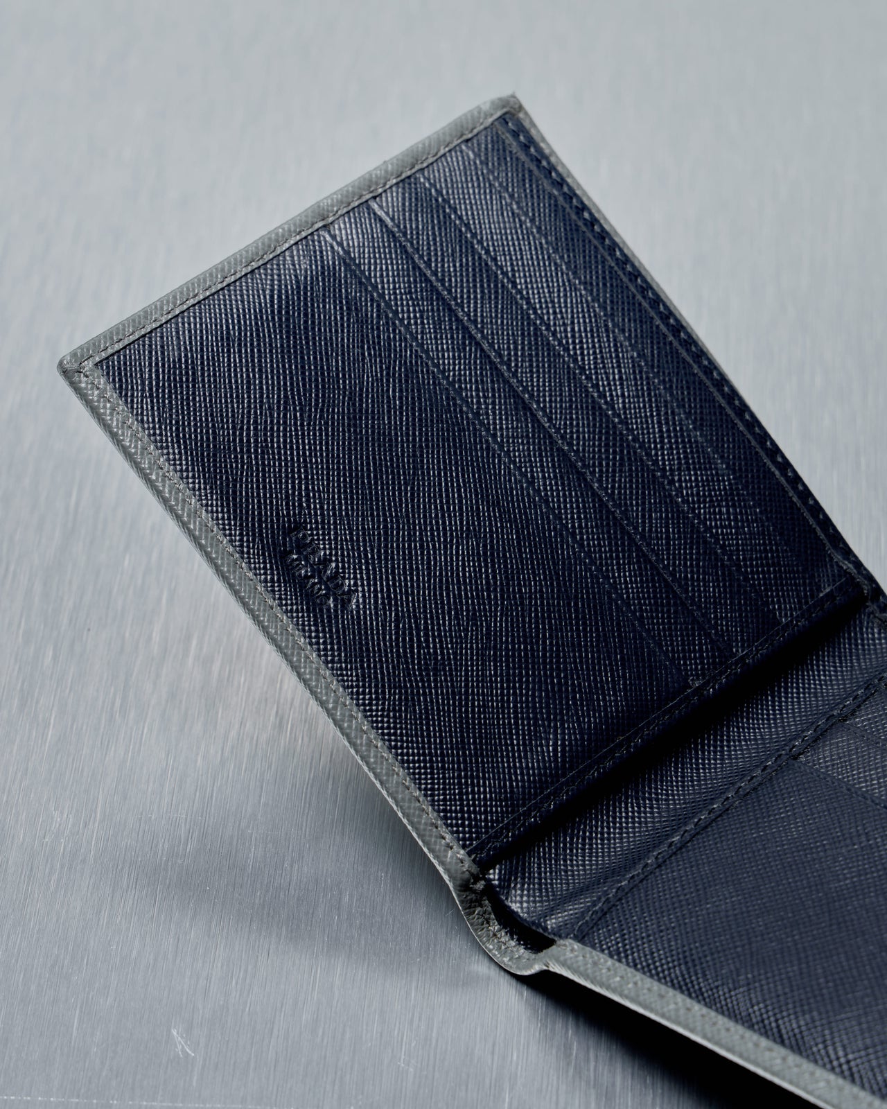 Gray Prada wallet on a textured gray surface