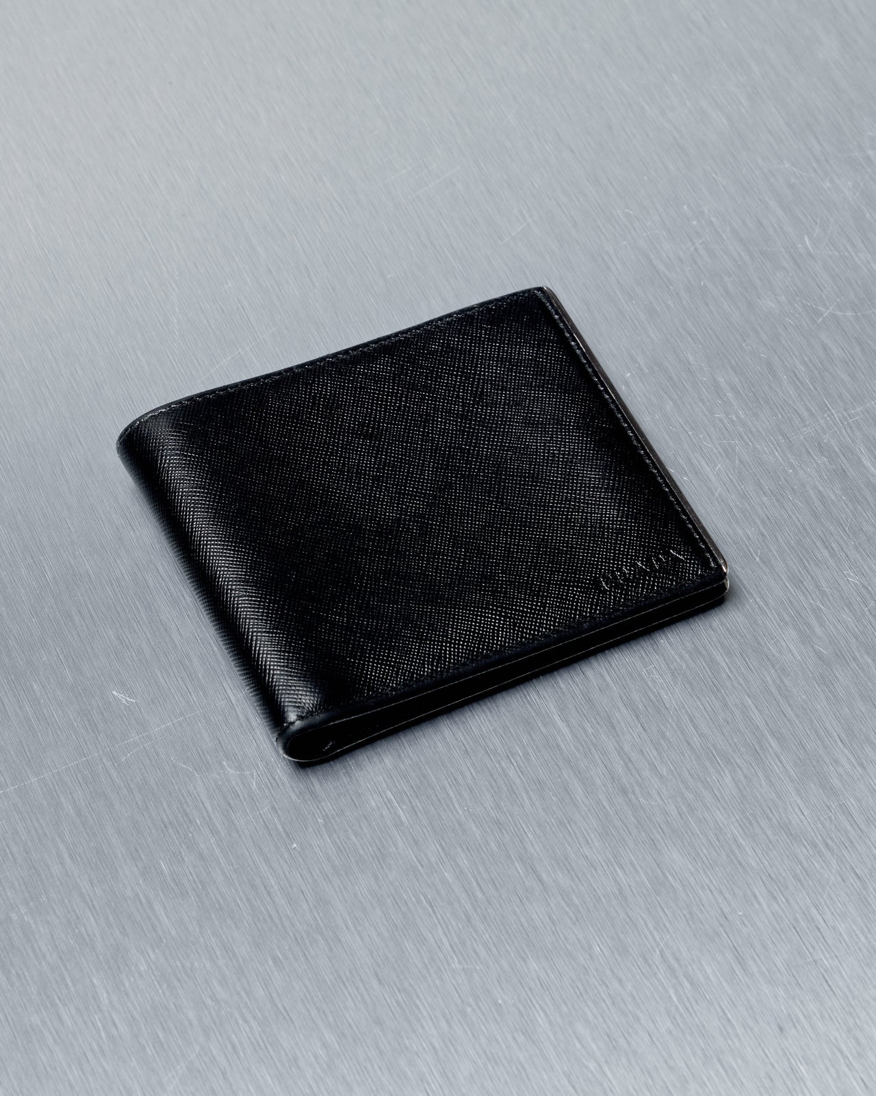 Black Prada leather wallet on a gray surface