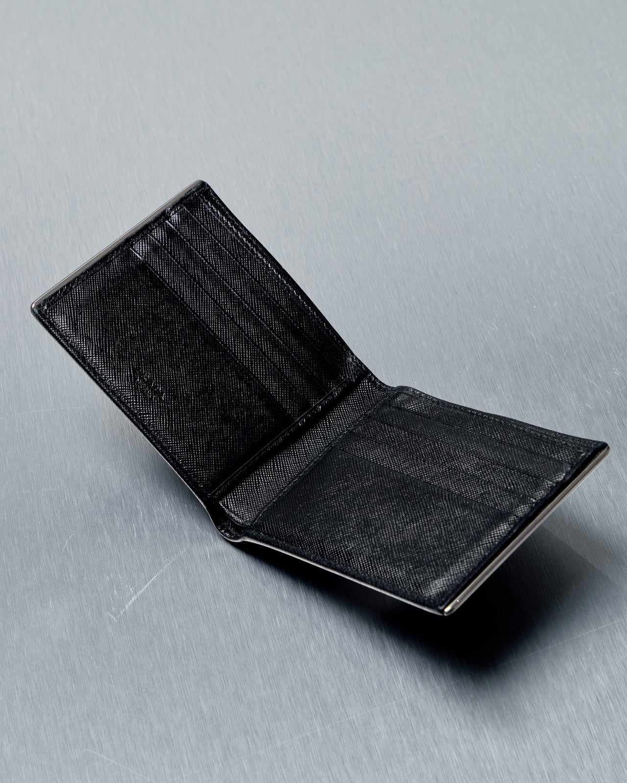 Black Prada leather wallet on a gray surface