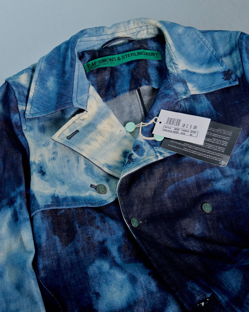 Blue patterned Raf Simons x Sterling Ruby coat on a mannequin against a light blue background