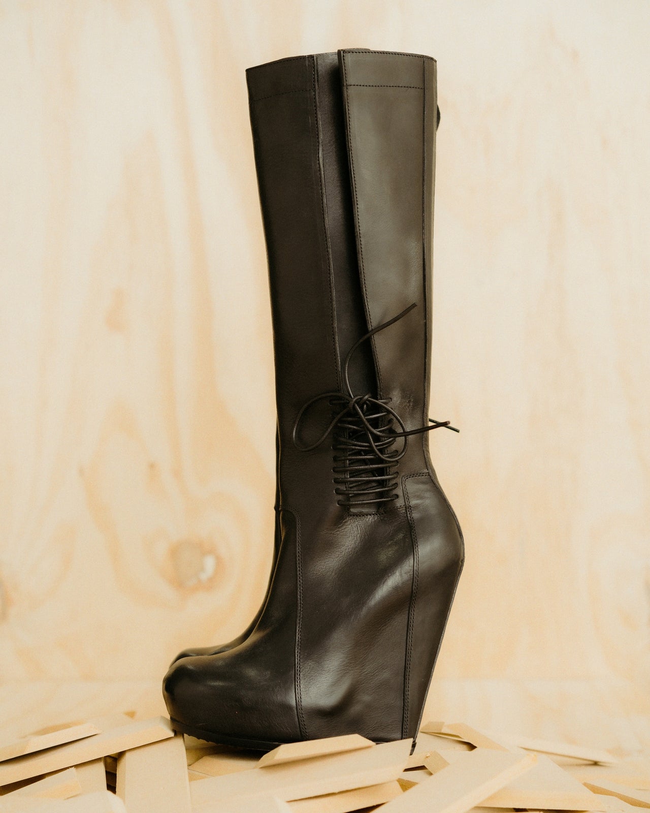 Black leather knee-high Rick Owens boot on a wooden surface
