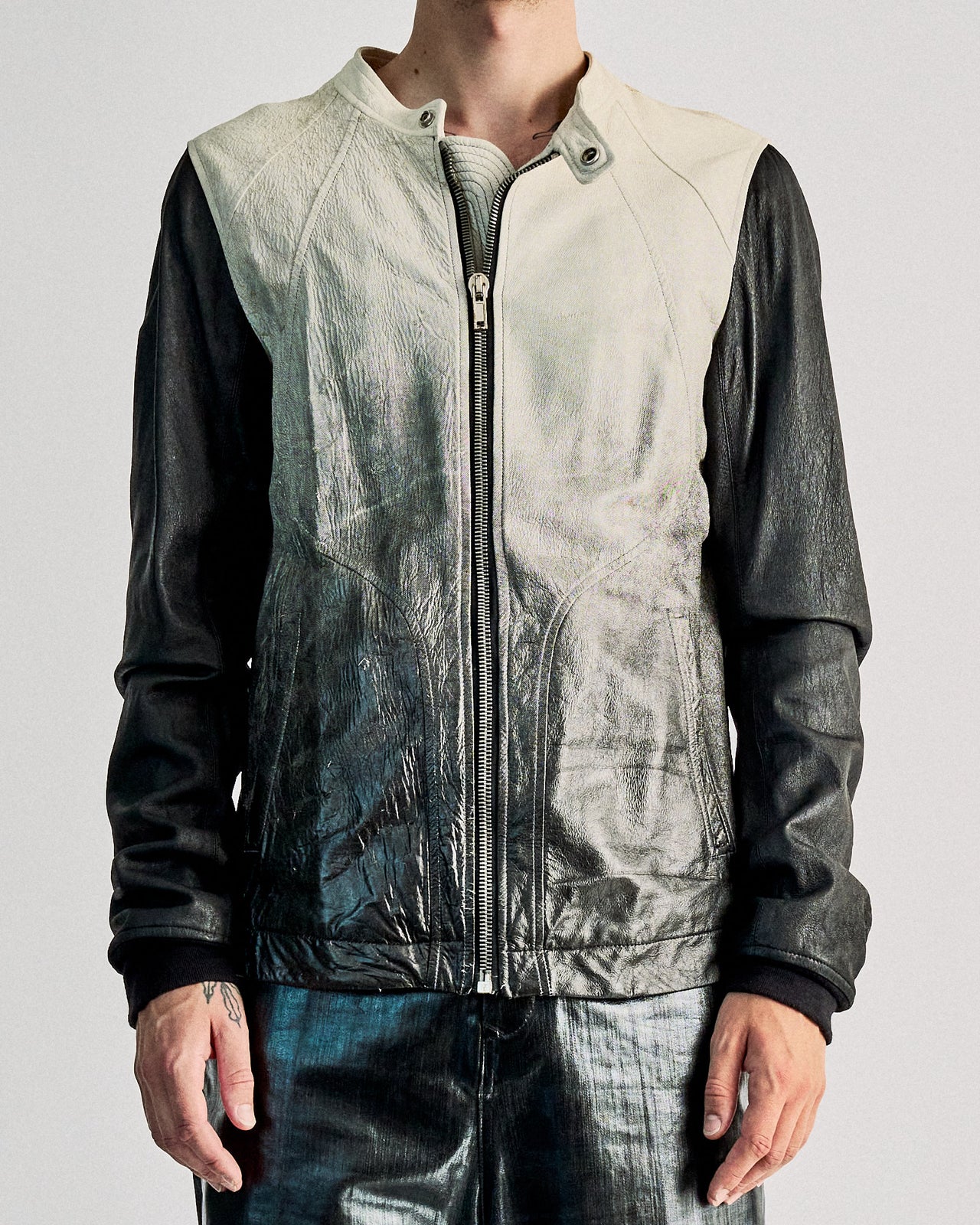 A person wearing a Rick Owens SS 2009 Gradient leather bomber jacket with a moto-style snap button collar and front zip closure. The jacket is primarily black with a gradient design that transitions into a gloss finish, and features two front pockets.