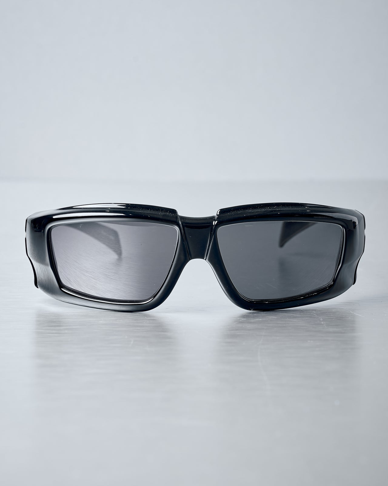 Black Rick Owens Nero sunglasses with reflective lenses on a light grey background
