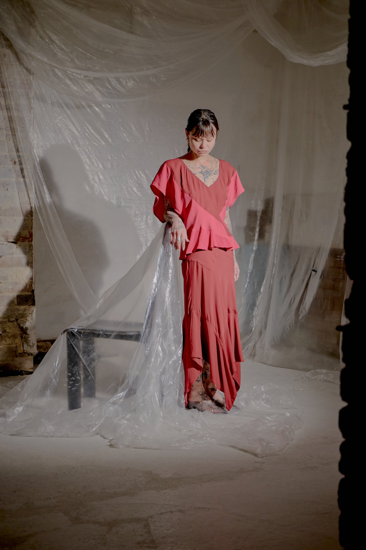Woman in a pink Saint Laurent outfit standing in front of draped fabric