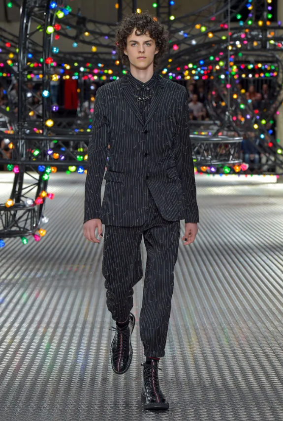 A pair of Dior pinstripe pants with drawstrings, elasticized waistband, side and back flap pockets, and embroidered detail.