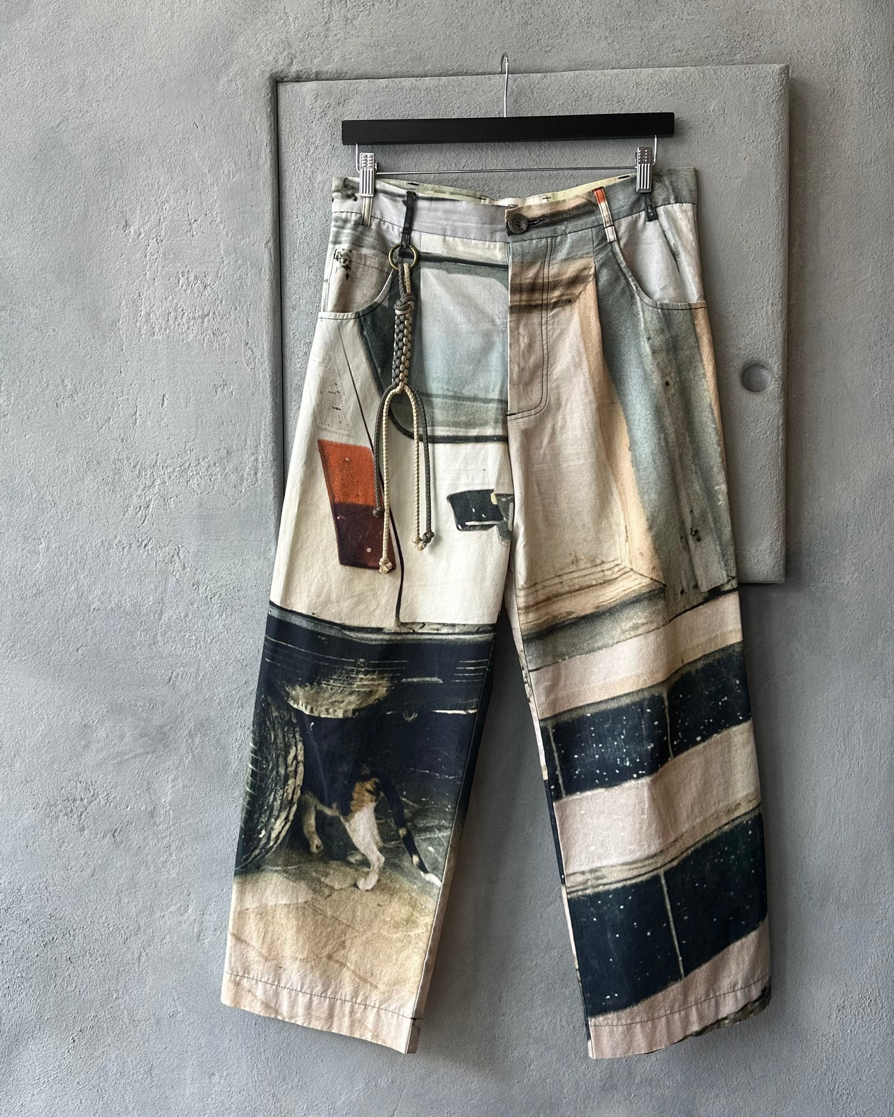 Song For The Mute Pants with abstract design hanging on a gray wall