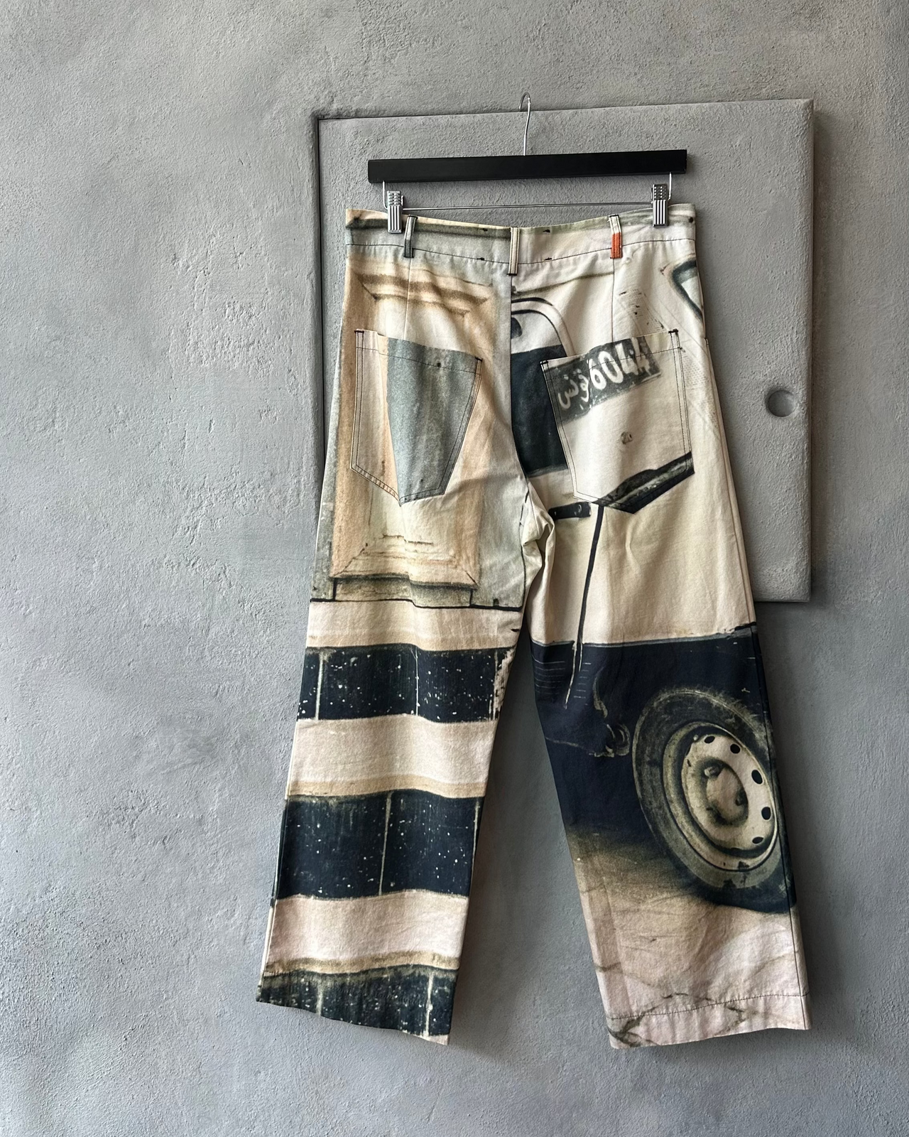 Song For The Mute Pants with abstract design hanging on a gray wall