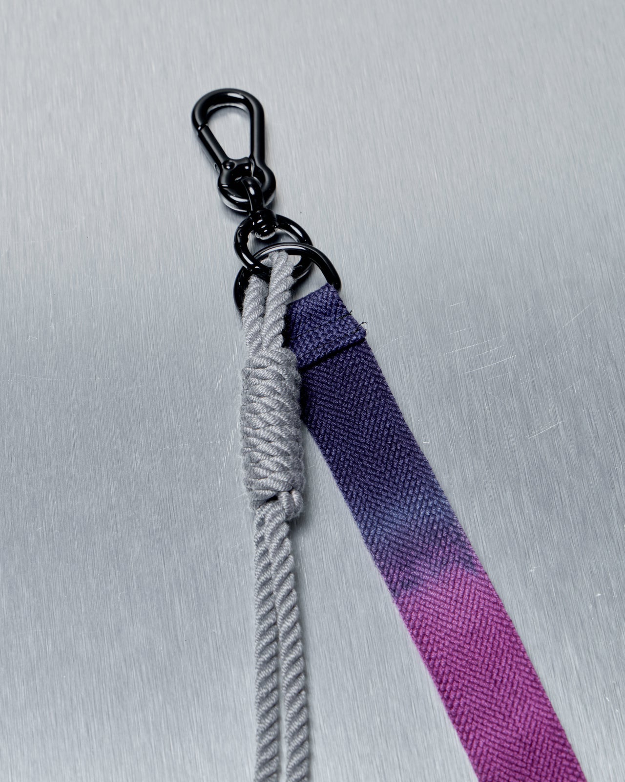 Gradient purple to gray Song For The Mute lanyard with metal clip on a light gray background