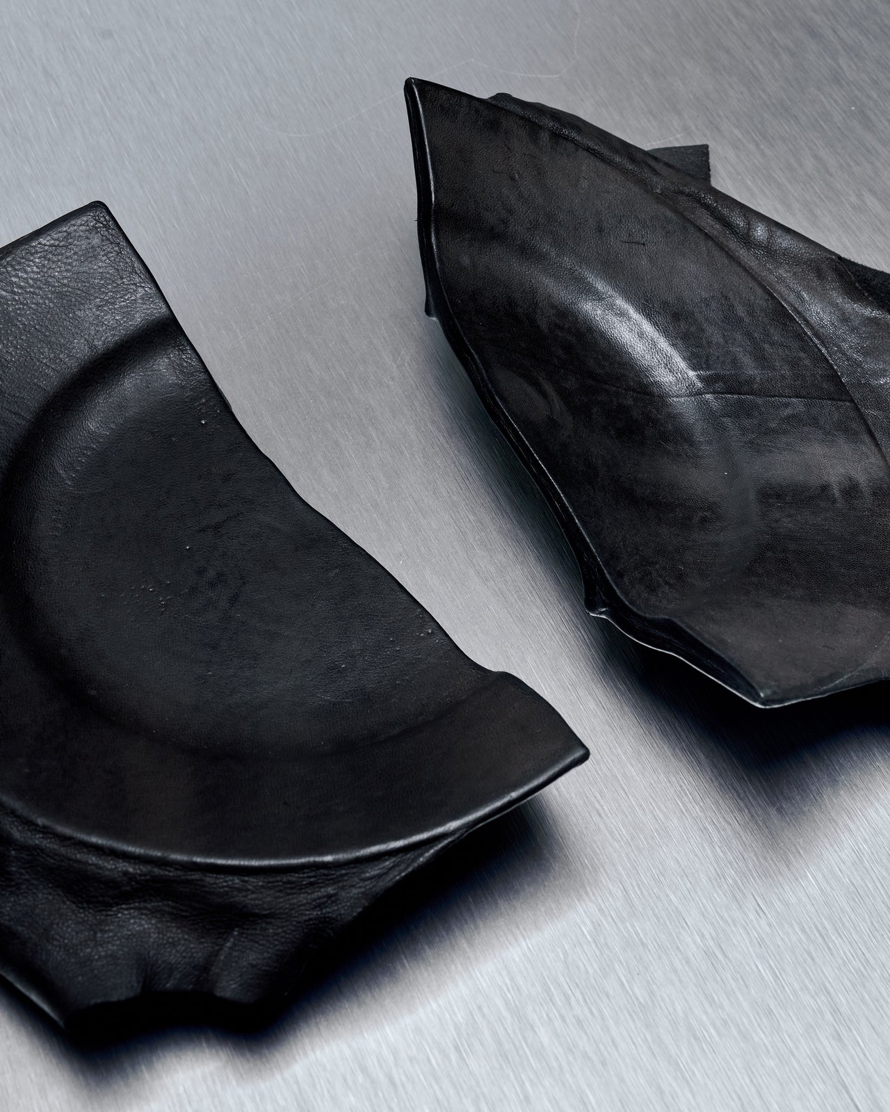 A photo of a ceramic plate from T.A.S Japan with a black lamb leather cover, showcasing the broken and repaired portions of the plate.