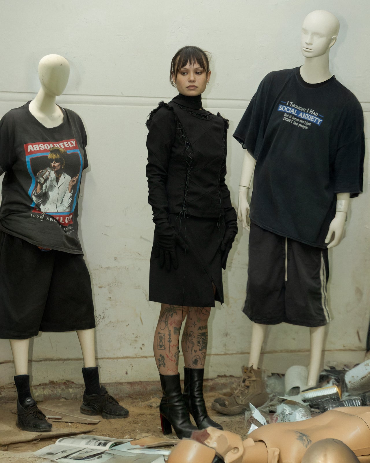 Person wearing a dark, textured Undercover outfit with gloves and boots on a dark background