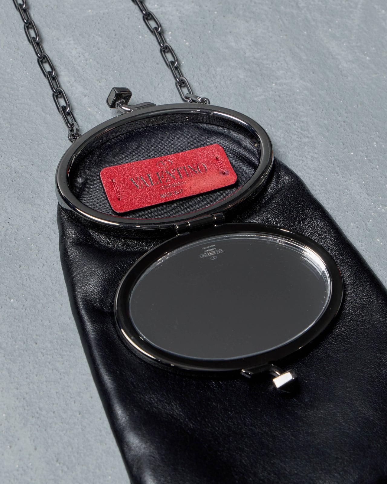 Black leather Valentino handbag with chain handle on a gray background