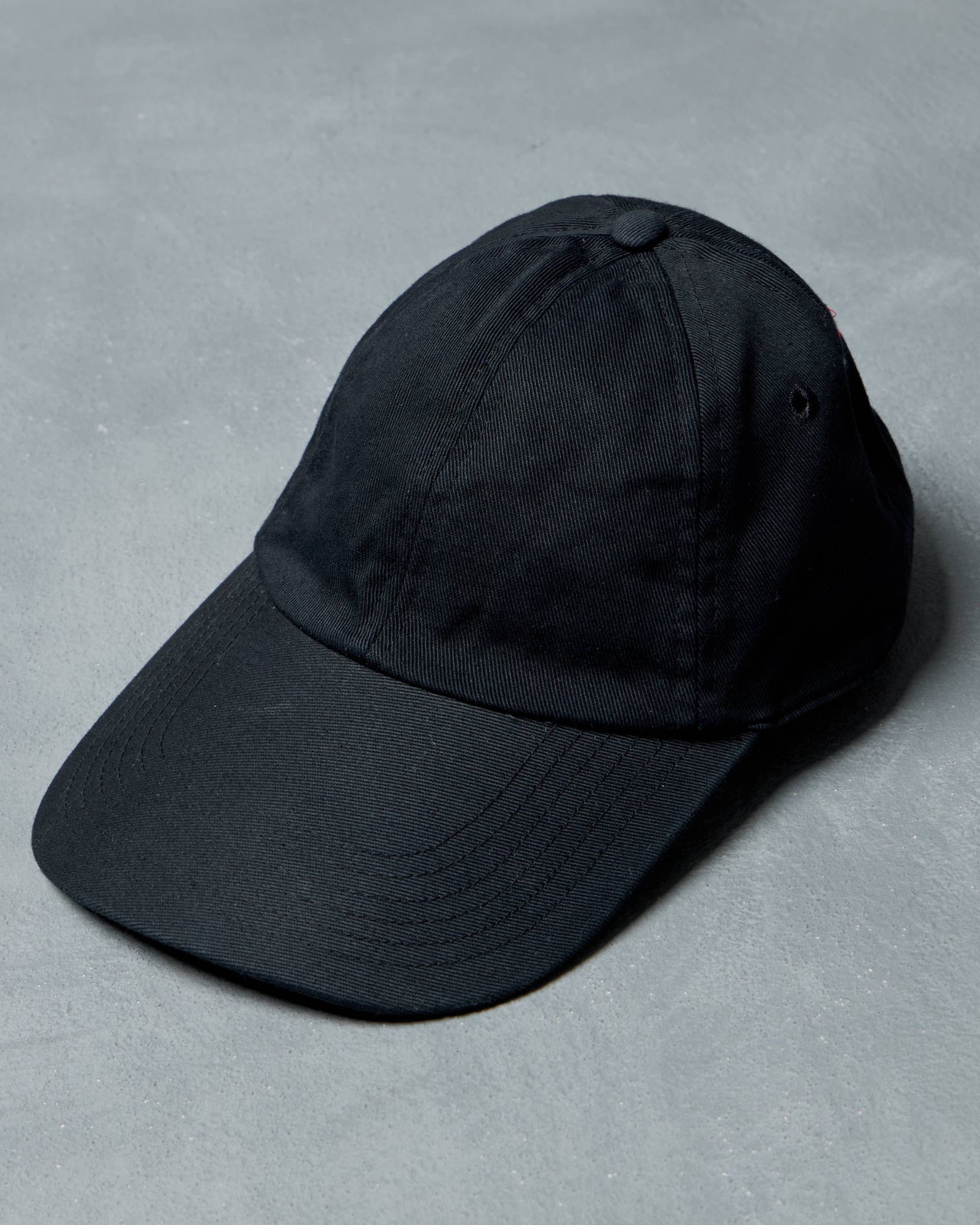 Black Vetements cap with red embroidered text on a gray background