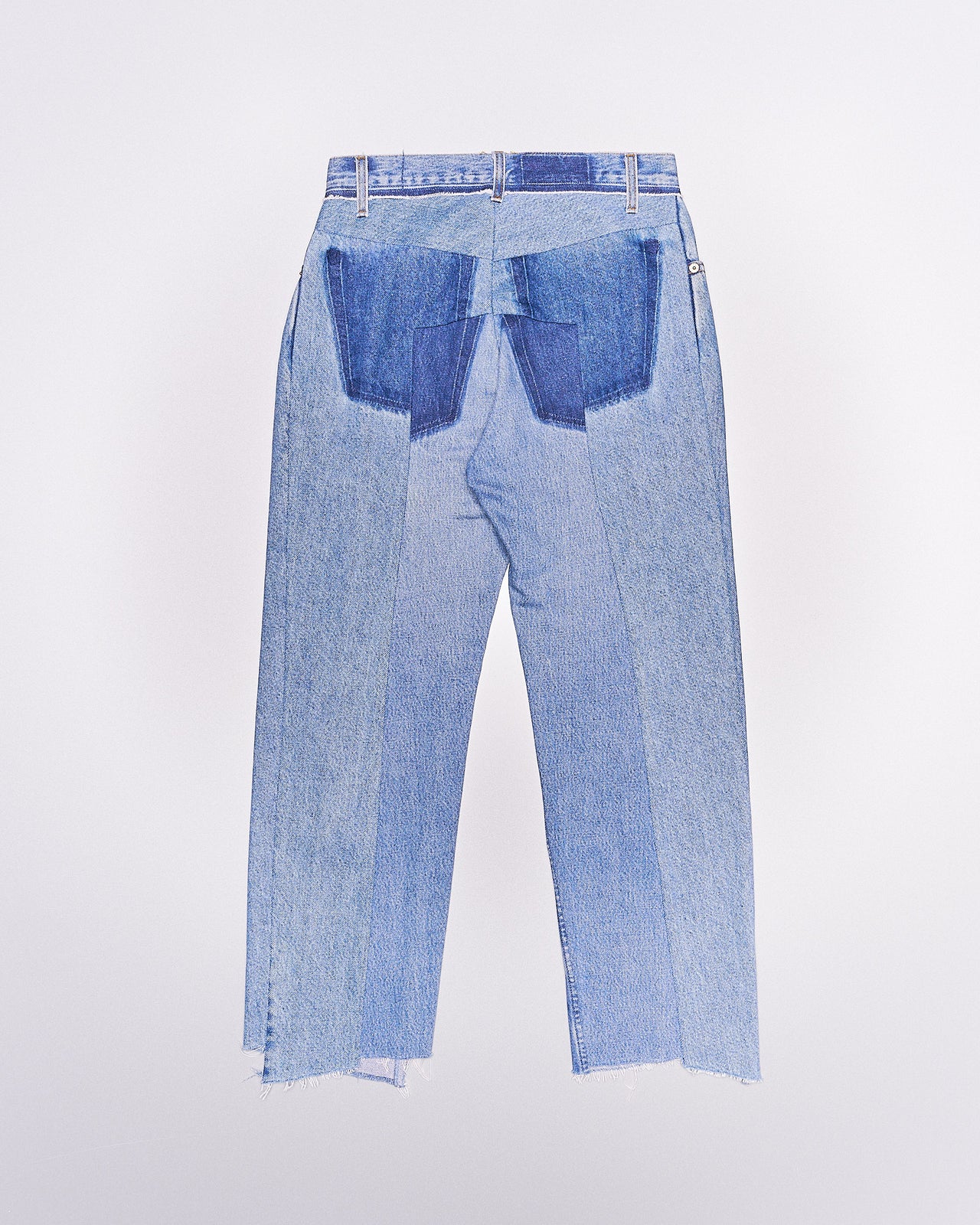 Two-tone blue denim Vetements jeans with frayed hems and a patchwork design, featuring alternating light and dark blue strips. Casual and modern style.