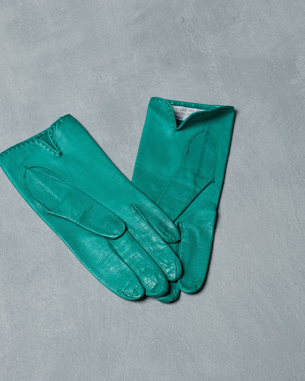 Pair of vintage teal gloves on a gray background