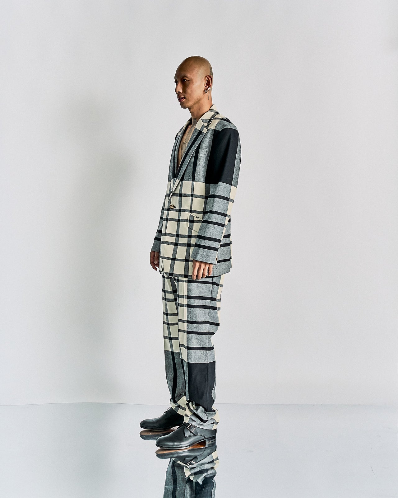 Model wearing a checkered Vivienne Westwood suit with a black turtleneck on a runway.