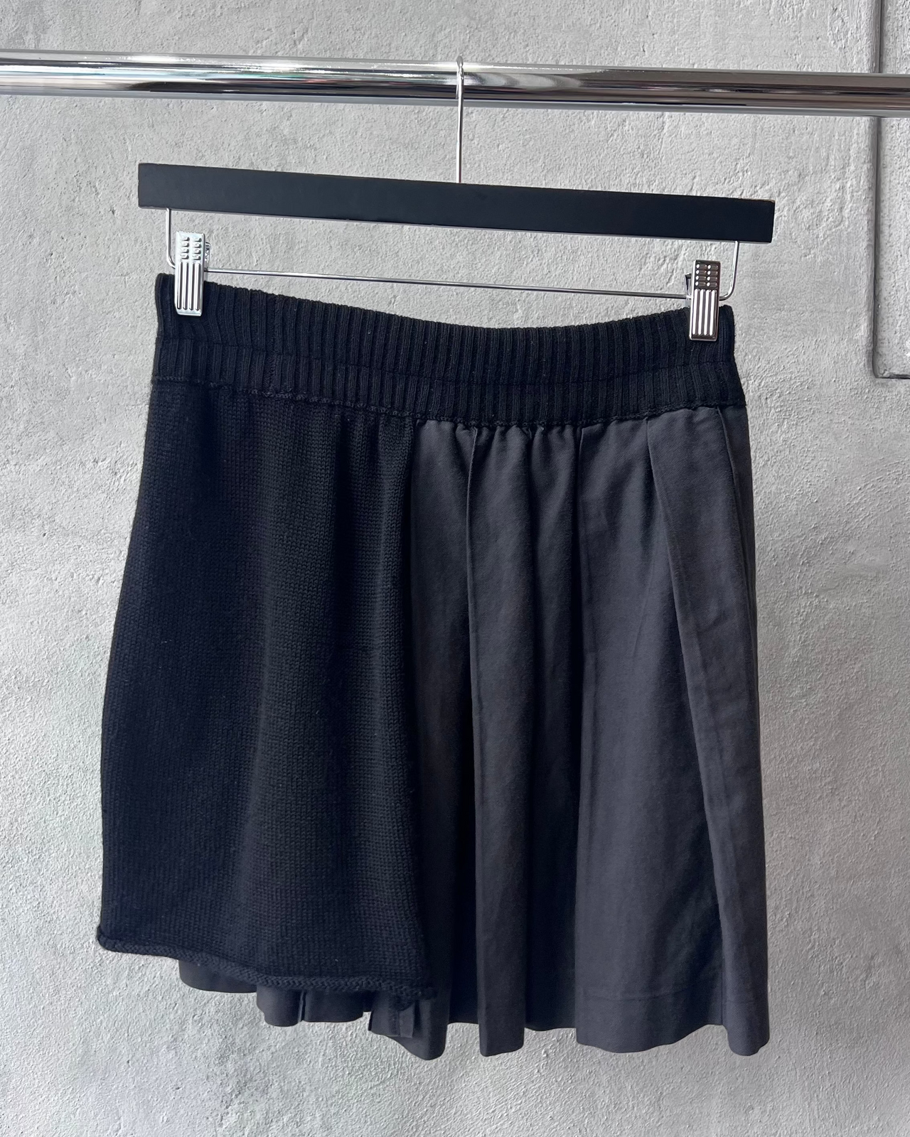 Black Y's By Yohji Yamamoto skirt hanging on a rack against a gray wall