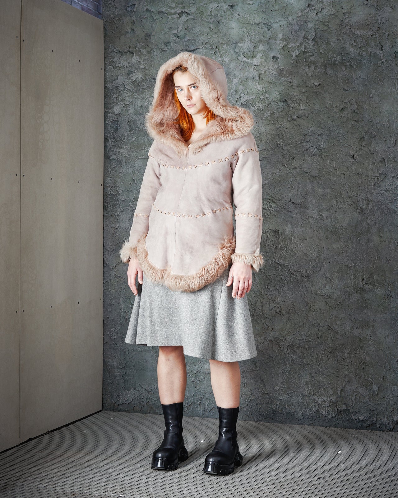 A model wearing a beige leather-stitched suede hooded pull-over with fur lining, from Alexander Mcqueen's 'The Overlook' Fall Winter 1999 collection.