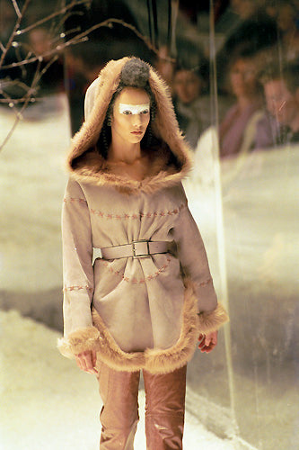 A model wearing a beige leather-stitched suede hooded pull-over with fur lining, from Alexander Mcqueen's 'The Overlook' Fall Winter 1999 collection.