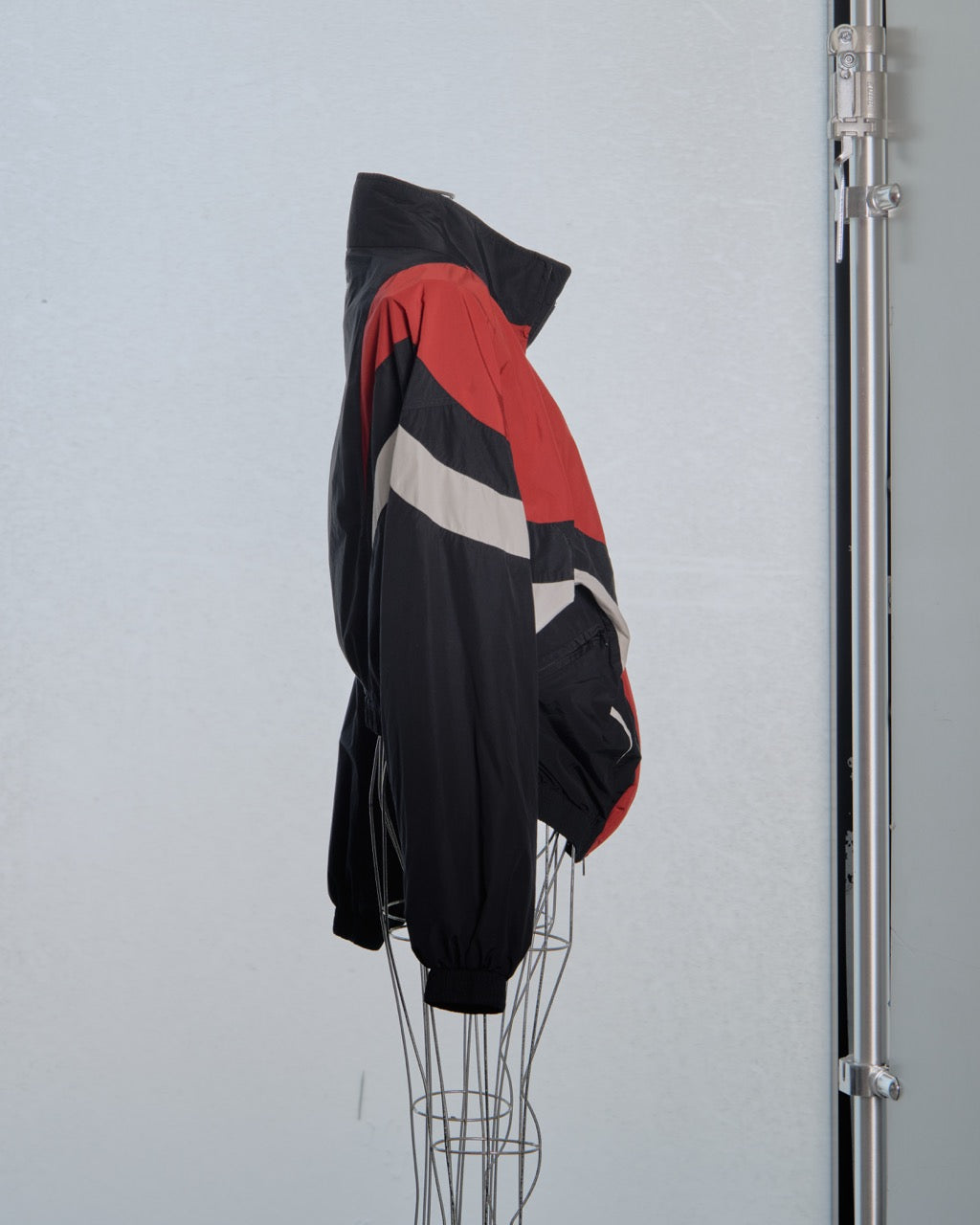 Black, red, and white Balenciaga jacket on a mannequin against a light gray background
