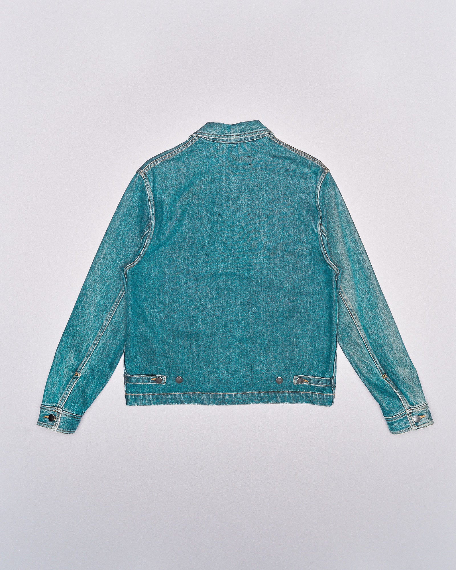 A stone washed denim Song For The Mute military jacket with a oversized silhouette, cropped rise and exaggerated front pockets. He is also wearing patterned trousers and beige boots.