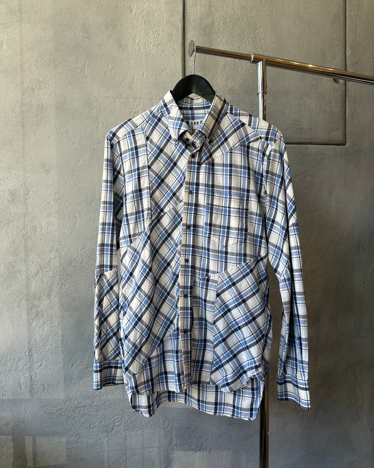 Blue and white AAR by Yohji Yamamoto plaid shirt on a hanger against a gray wall