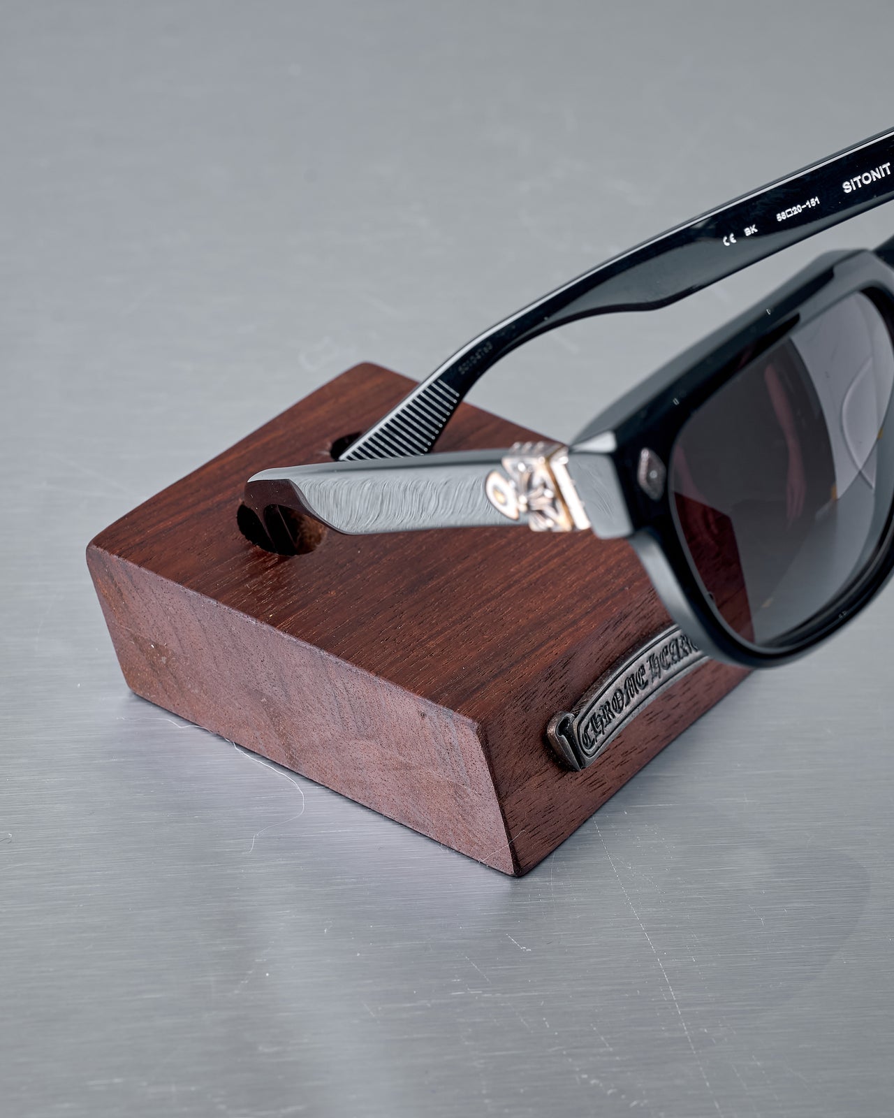 Wooden block with two holes and a metal logo plaque on the front