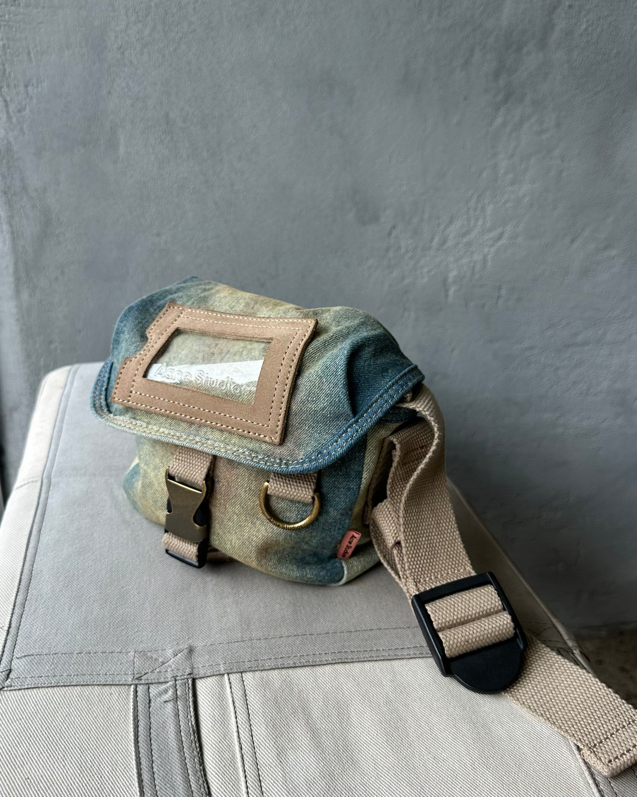 Denim Acne Studios bag with a strap on a gray surface