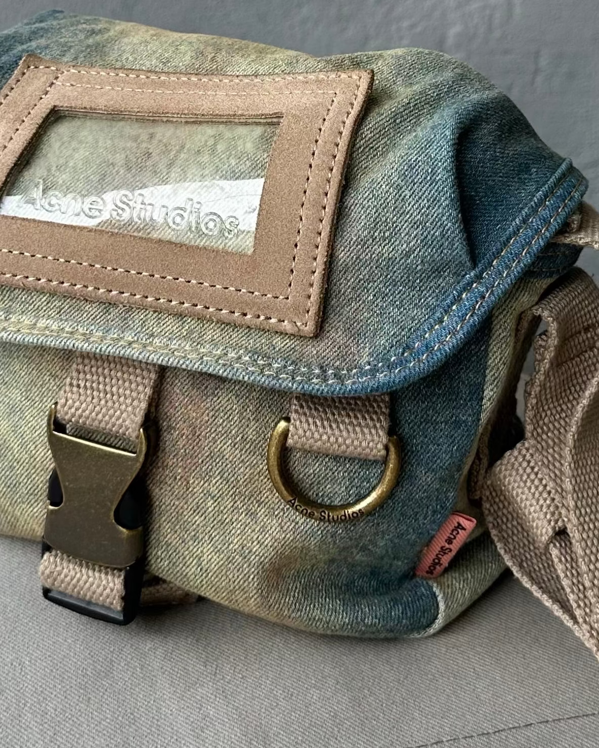 Denim Acne Studios bag with a strap on a gray surface