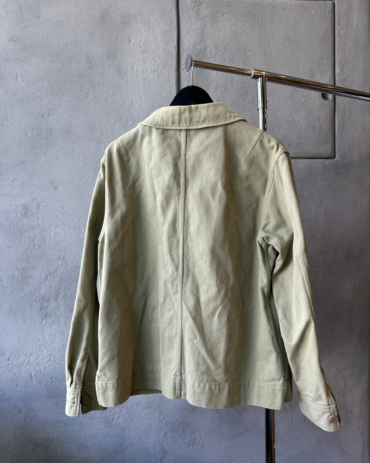 Beige Acne Studios jacket on a hanger against a gray wall