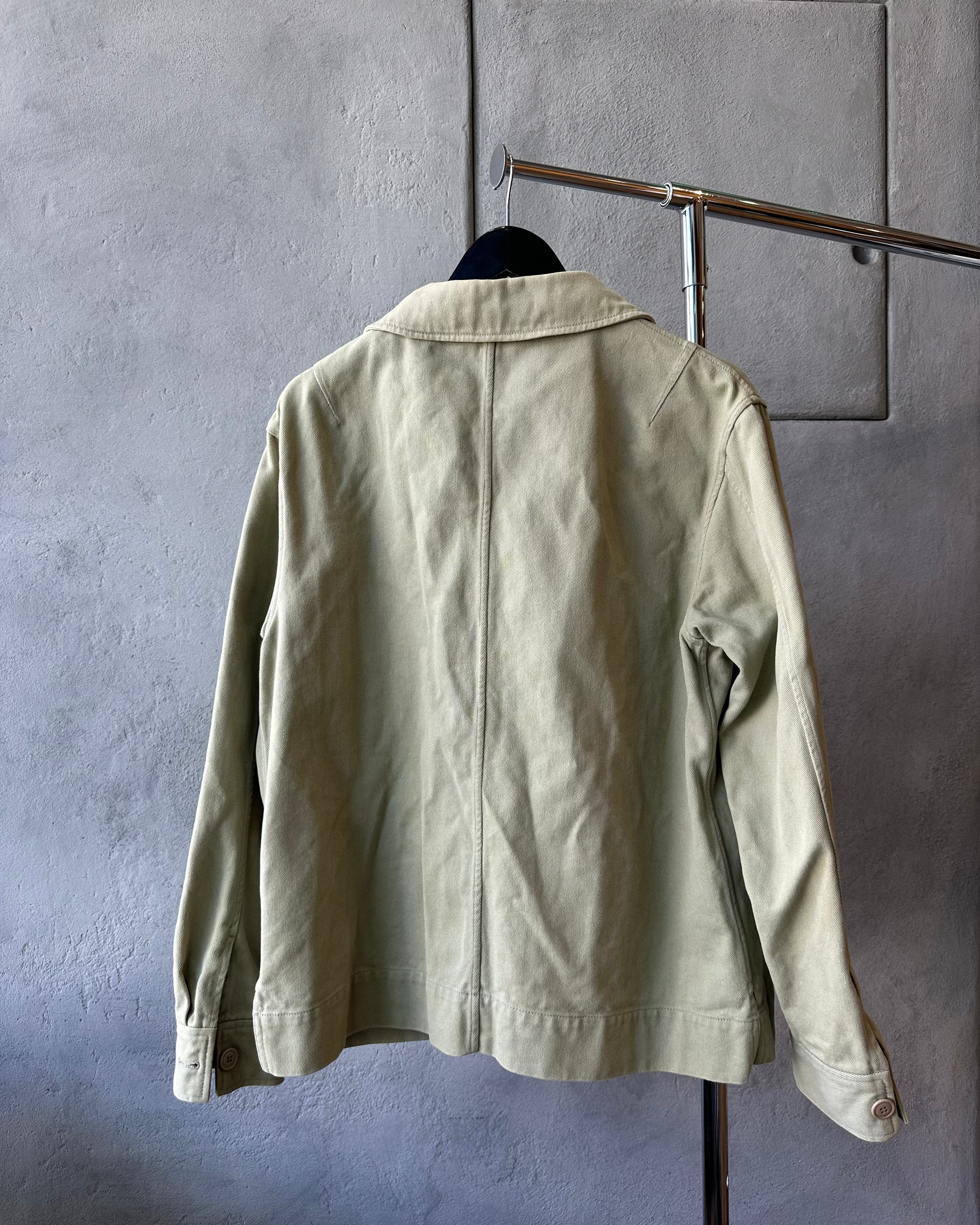 Light green Acne Studios jacket hanging on a rack against a gray wall