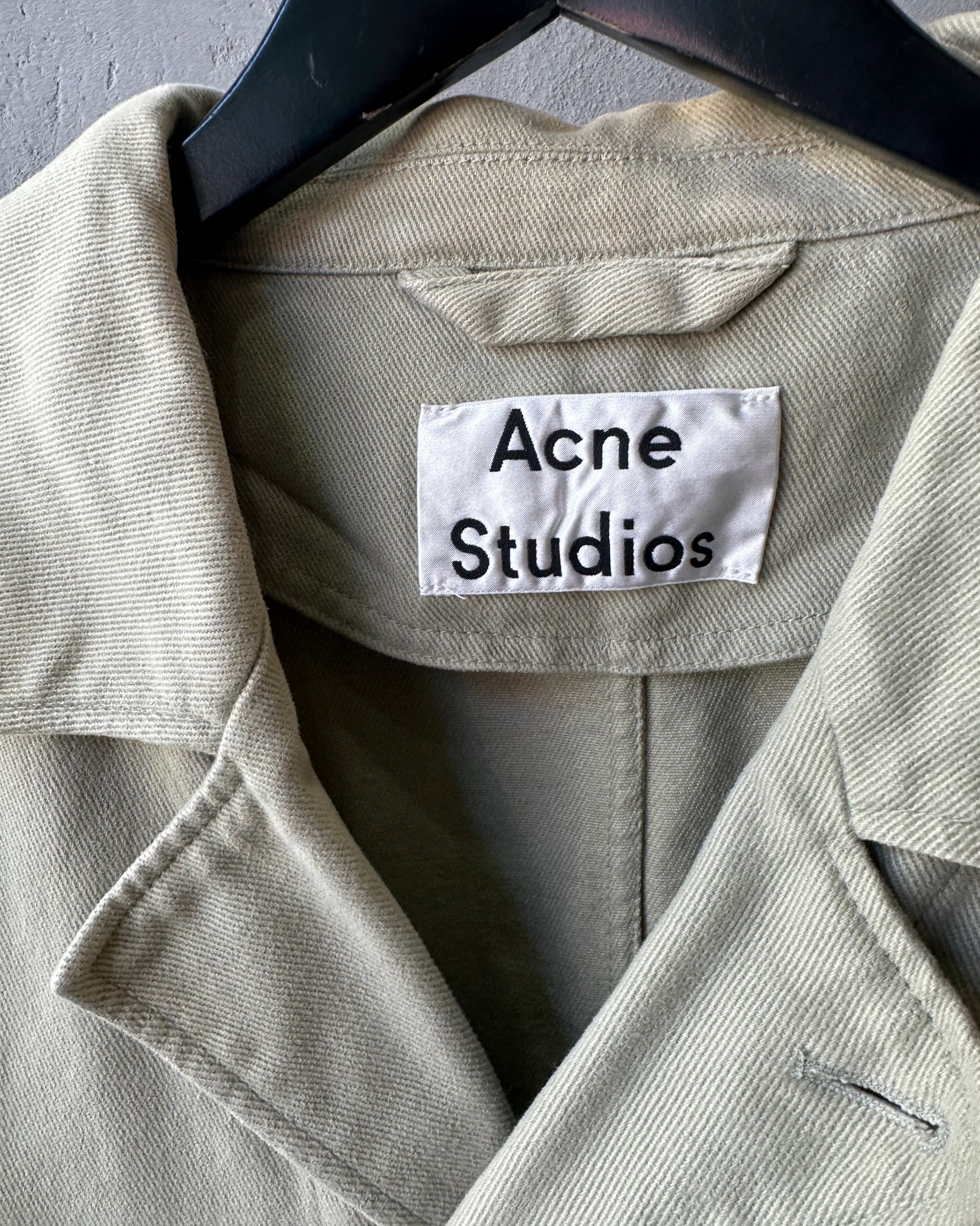 Beige jacket with 'Acne Studios' label on a hanger