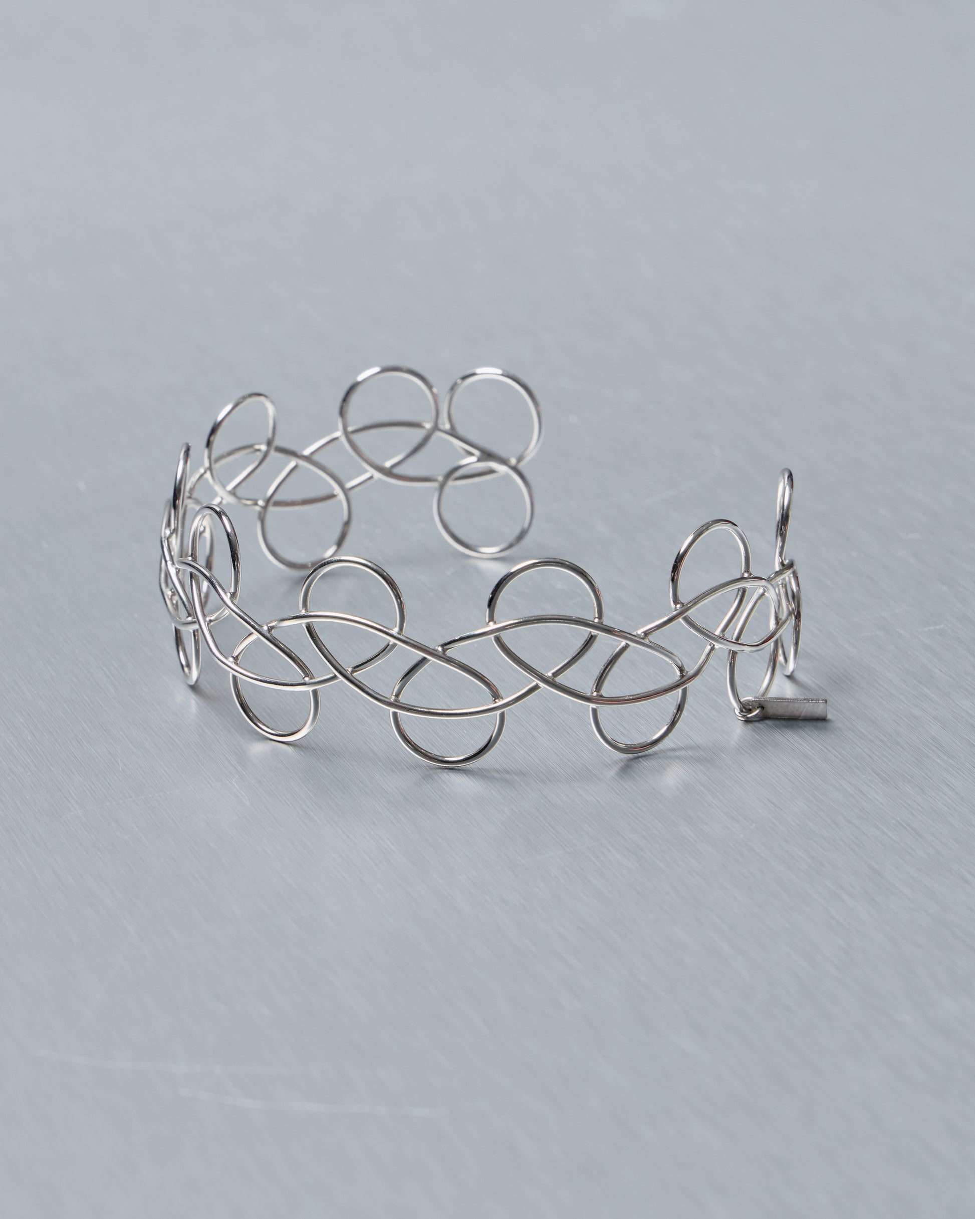 Silver wire Acne Studios choker necklace on a gray background