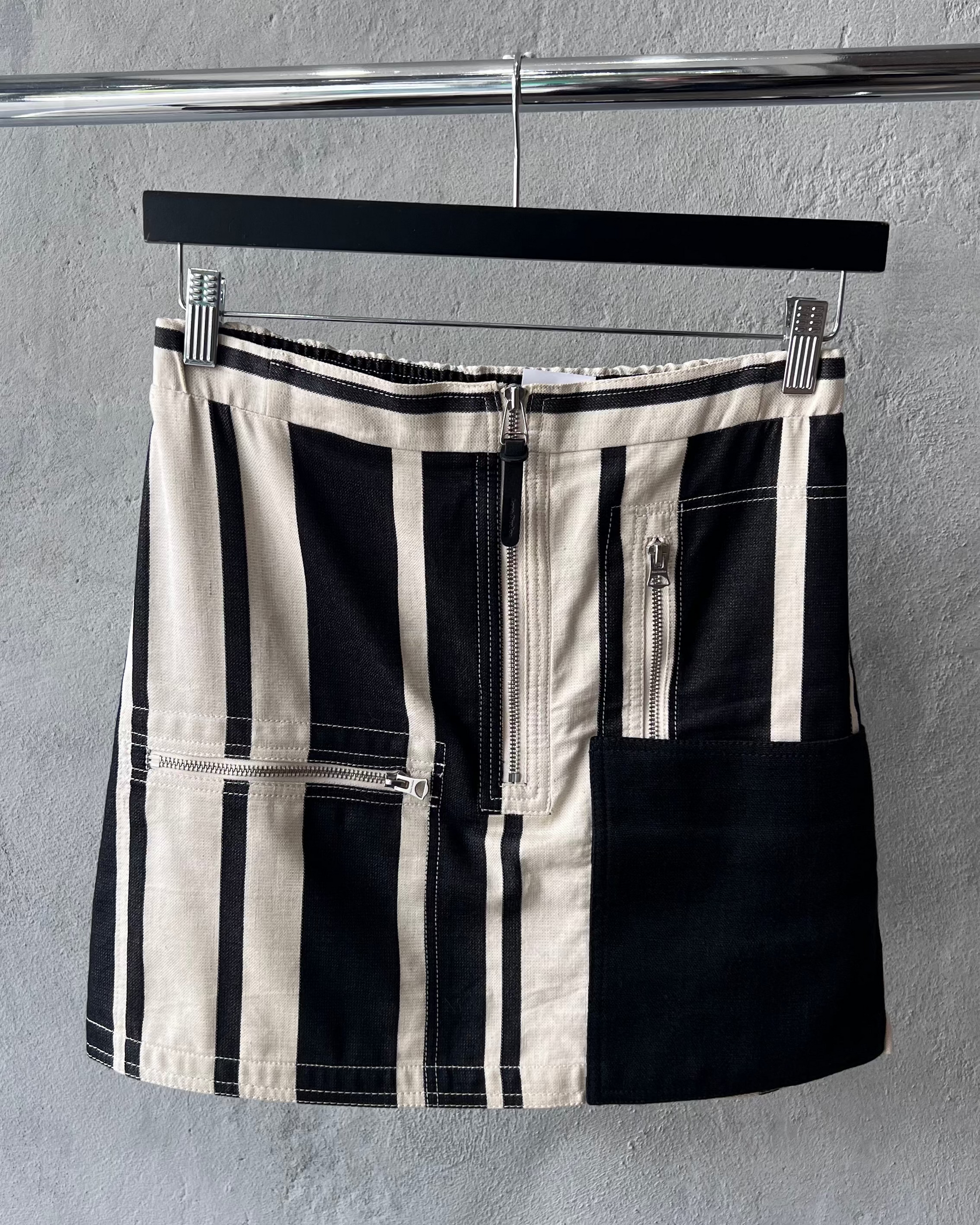 Black and white checkered Acne Studios skirt on a hanger against a gray background