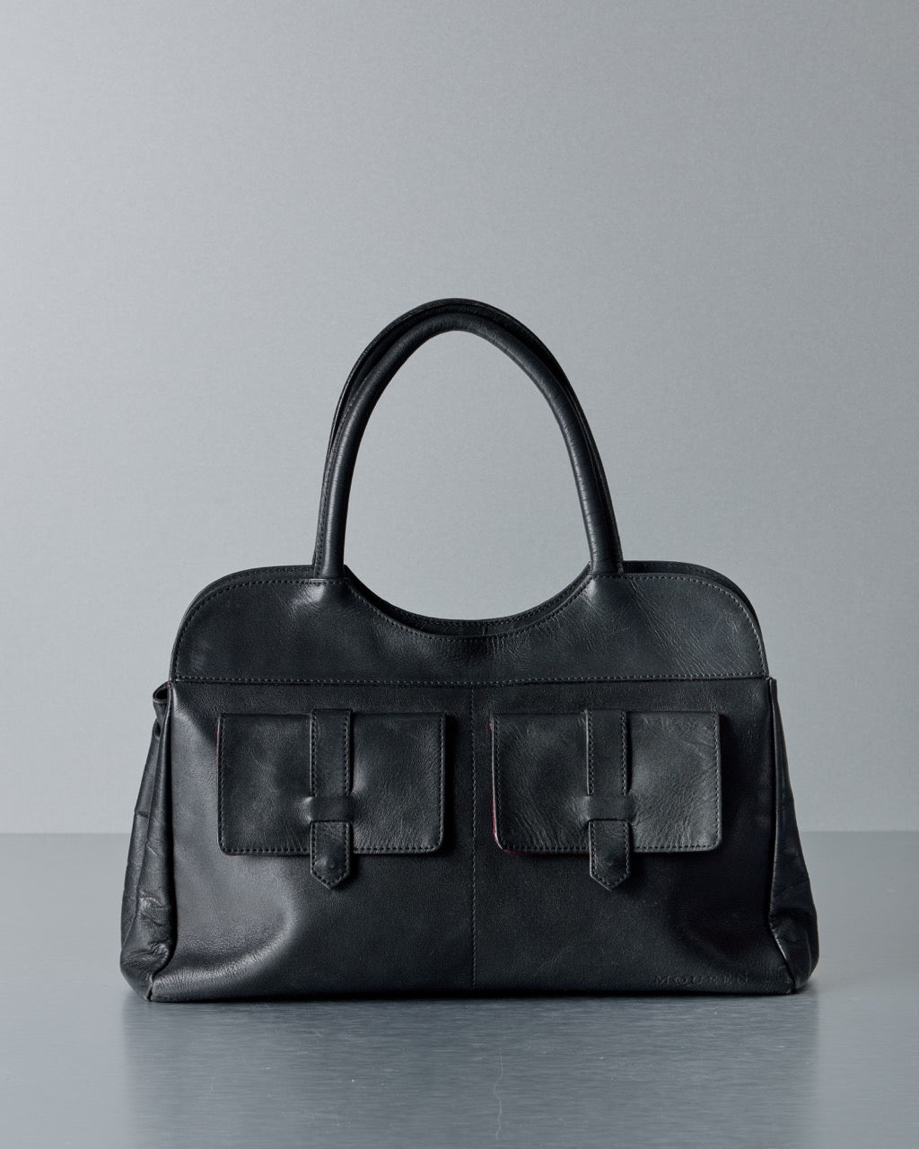 Black Alexander McQueen handbag on a light gray tiled floor