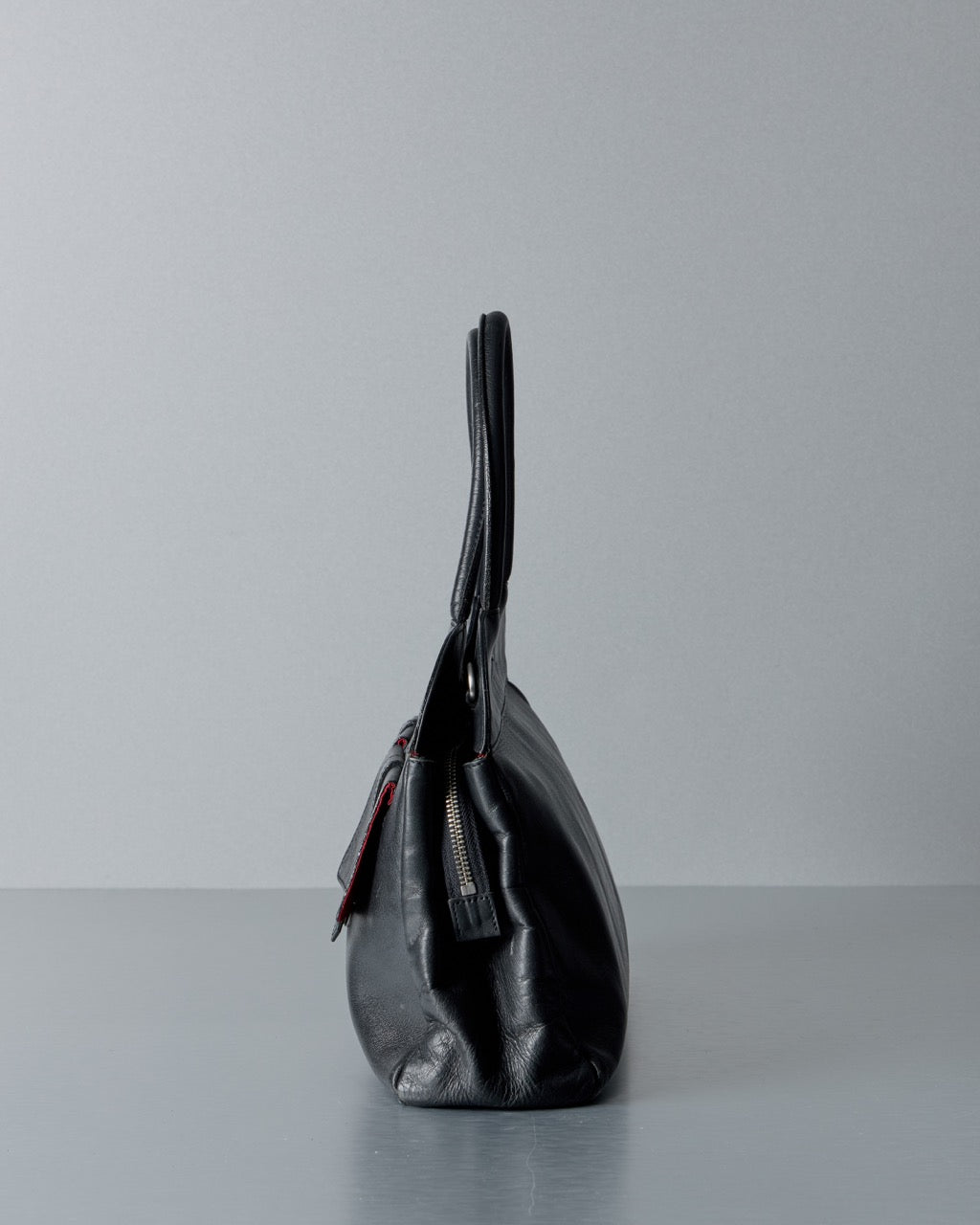 Black leather Alexander McQueen handbag on a gray surface with a light gray background