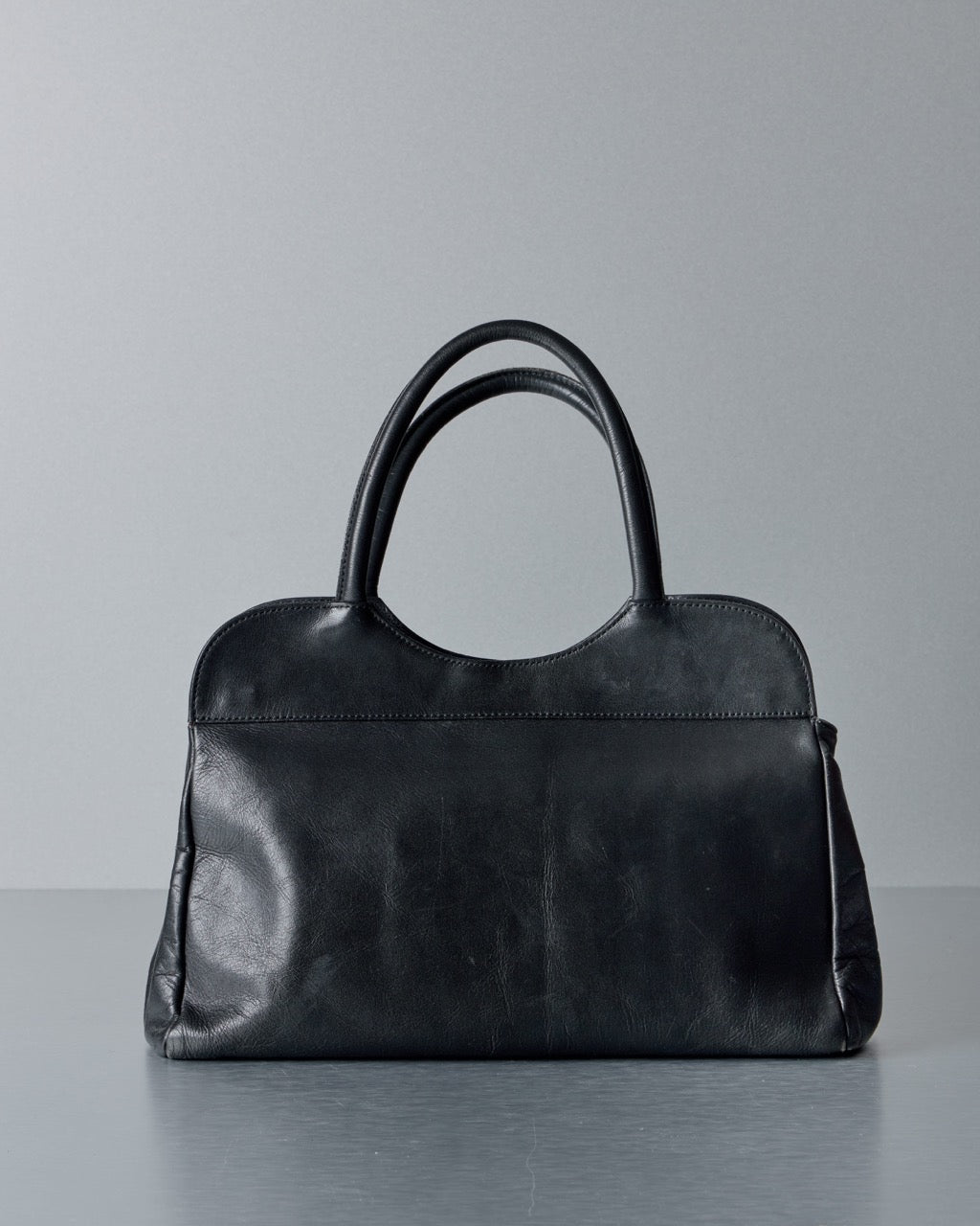 Black leather Alexander McQueen handbag on a gray background